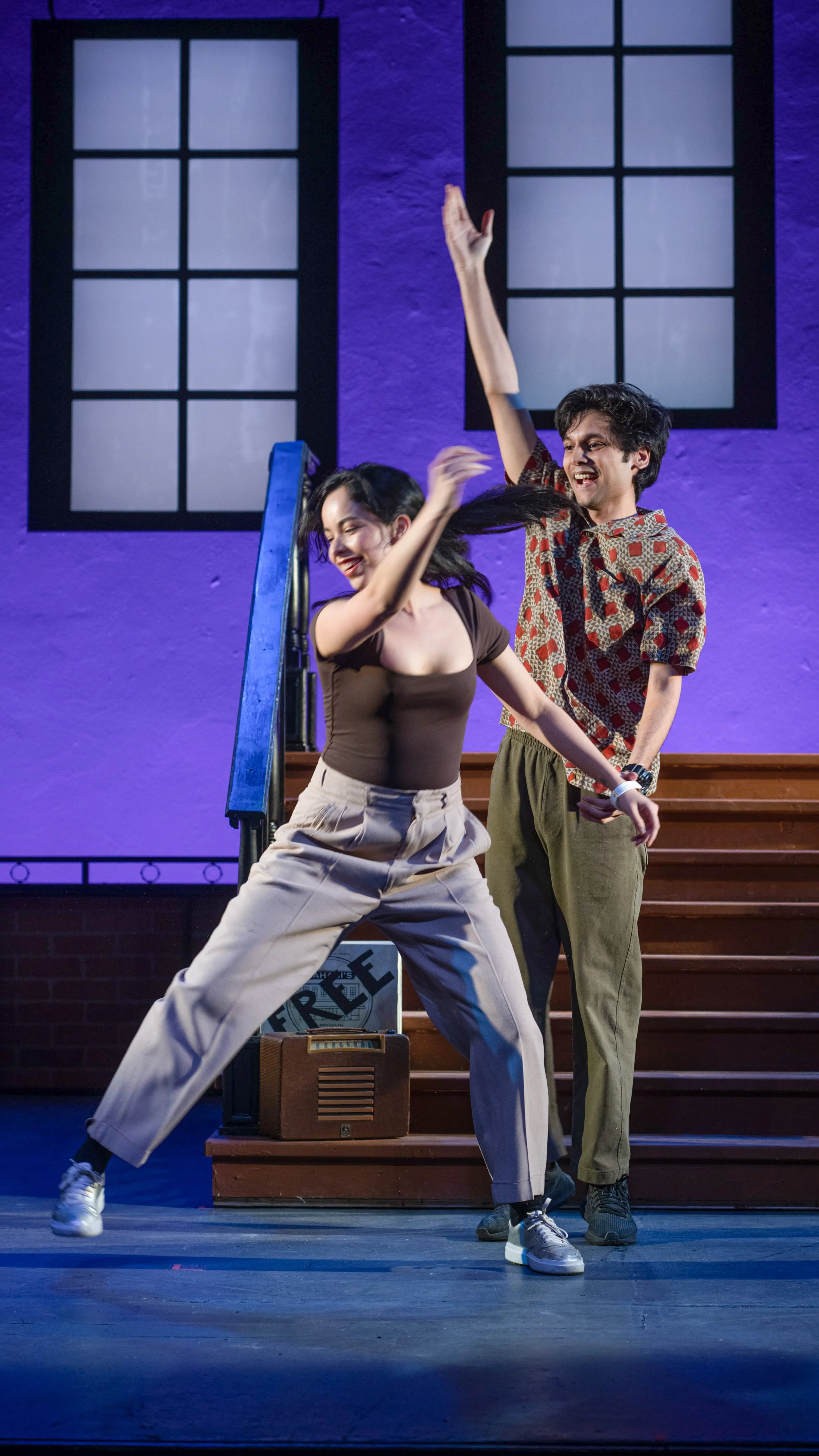 Two dancers move across the stage in front of the stoop set in Stoop Songs.