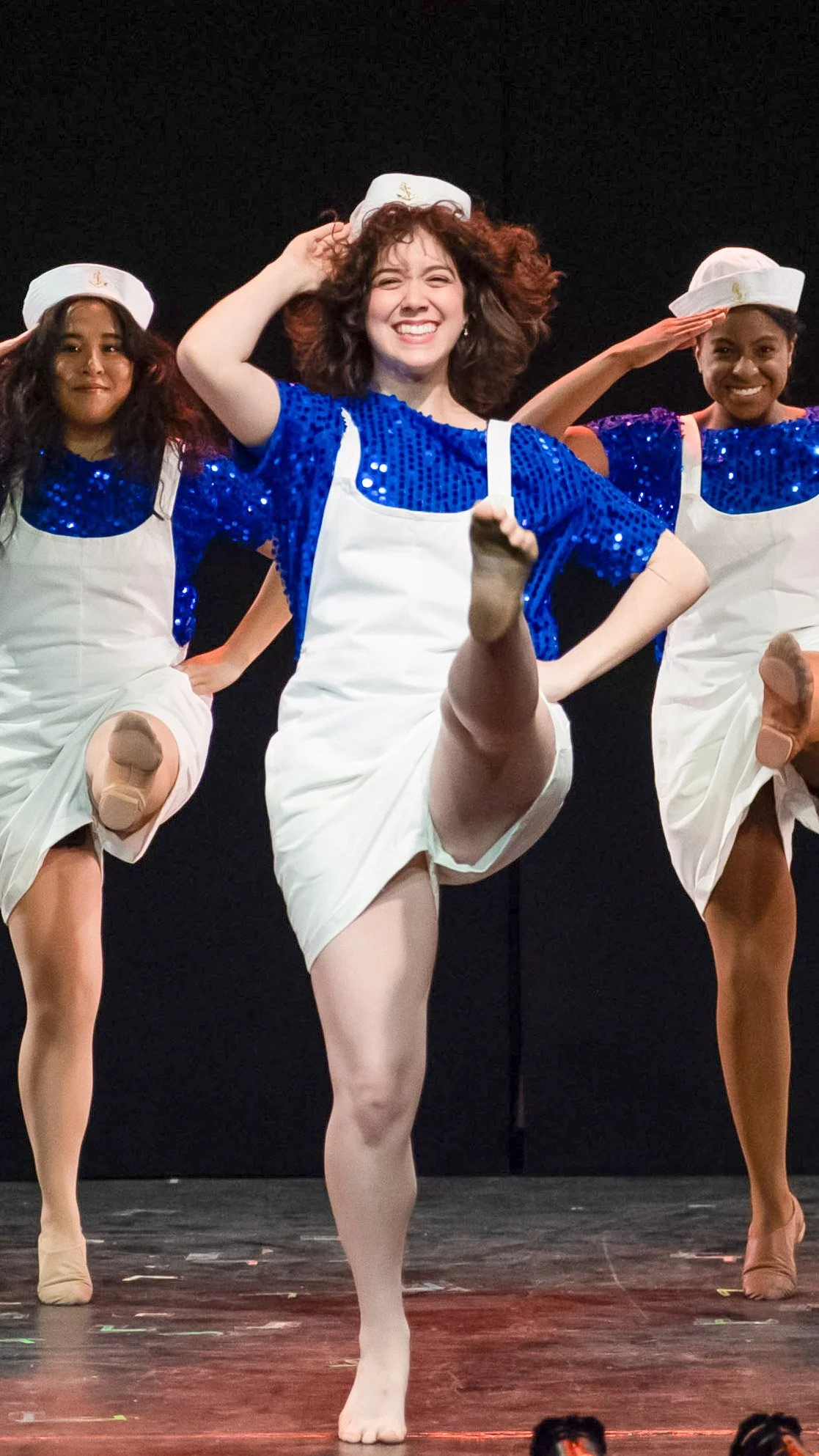 Dancer in a white-and-blue uniform performs a high kick in Dance Nation.