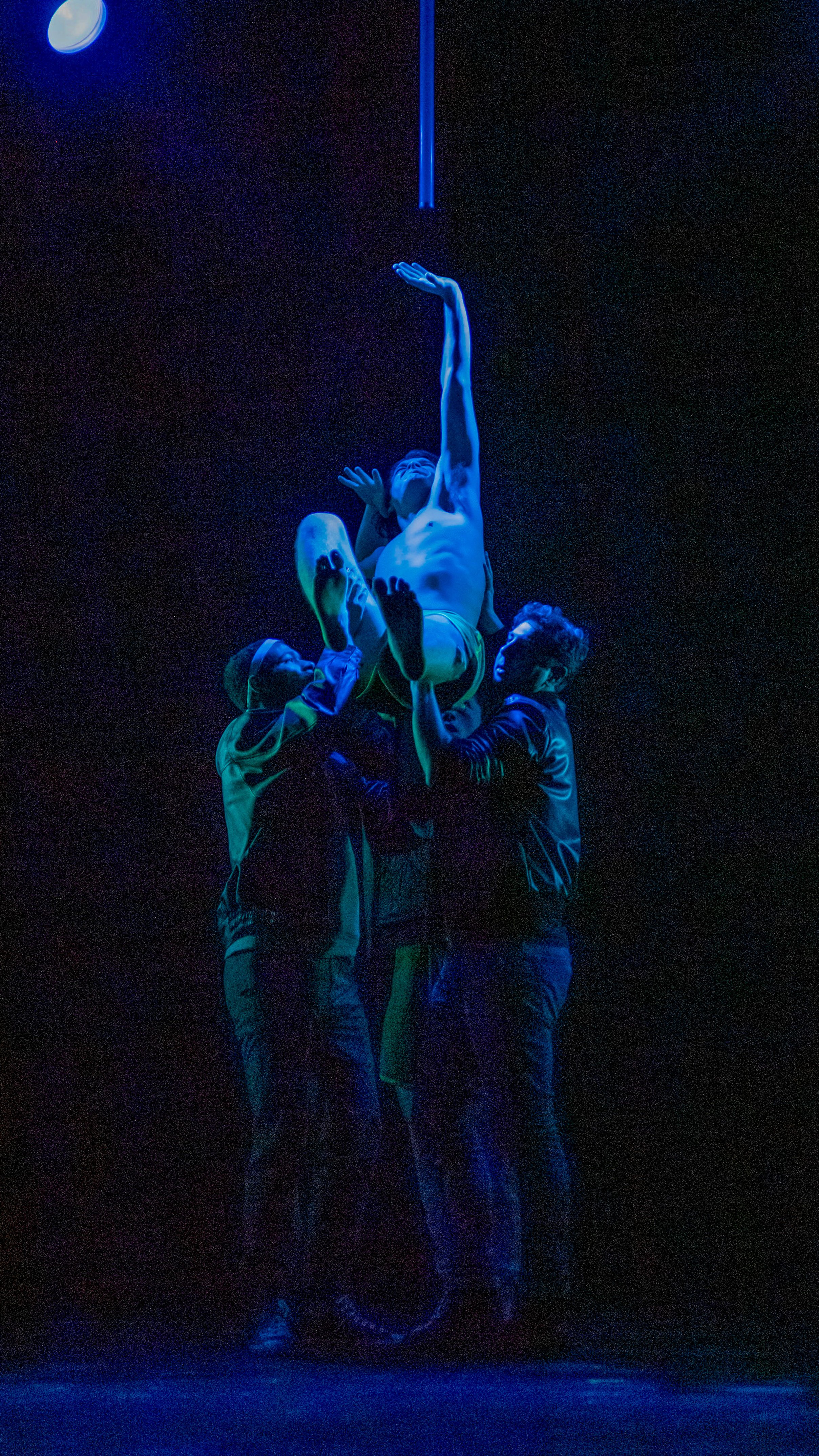 Two performers embrace beneath a narrow blue spotlight in Let the Right One In.