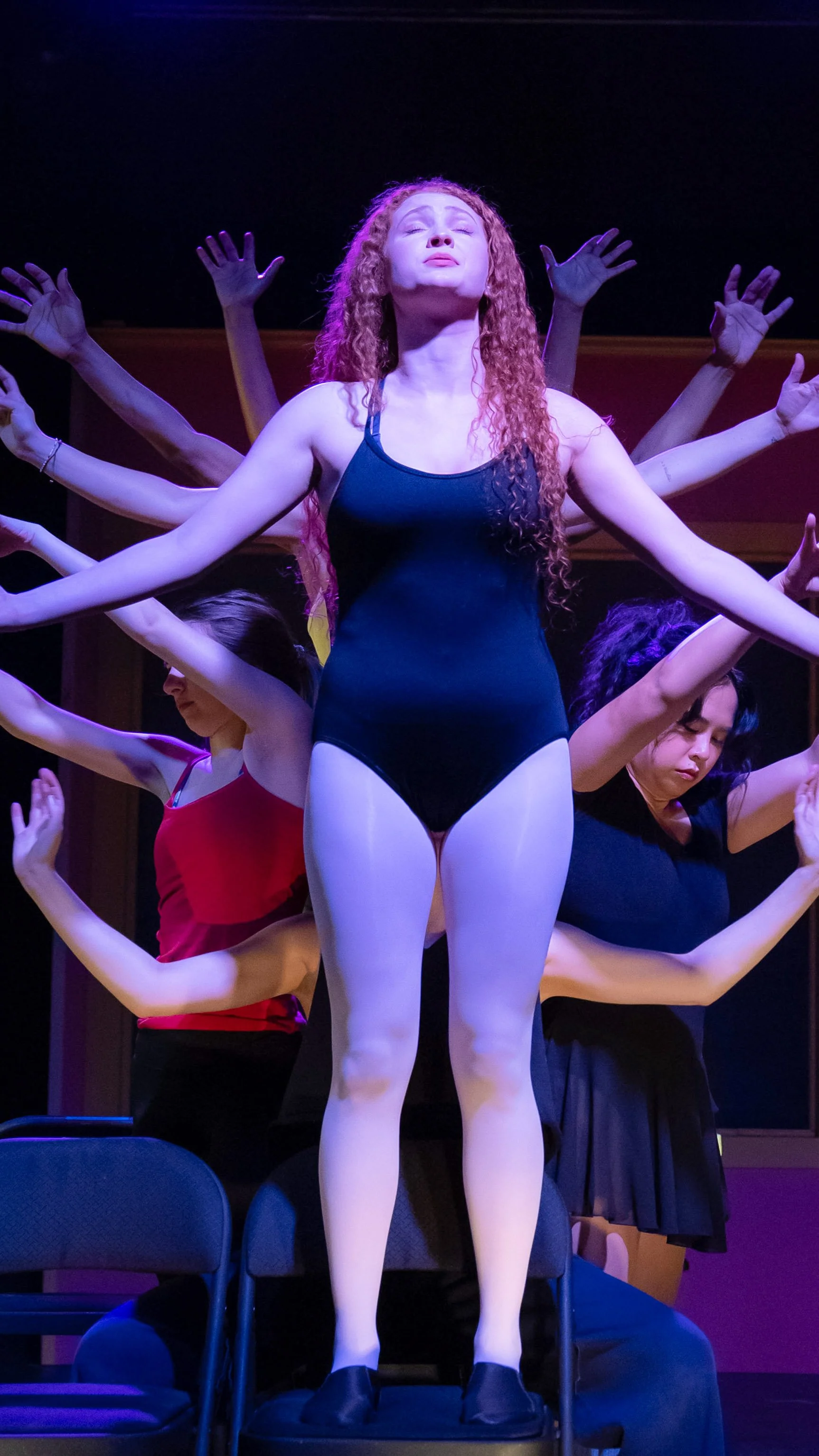 Dancer in a blue leotard stands center as the ensemble forms a radiating arm pattern in Dance Nation.