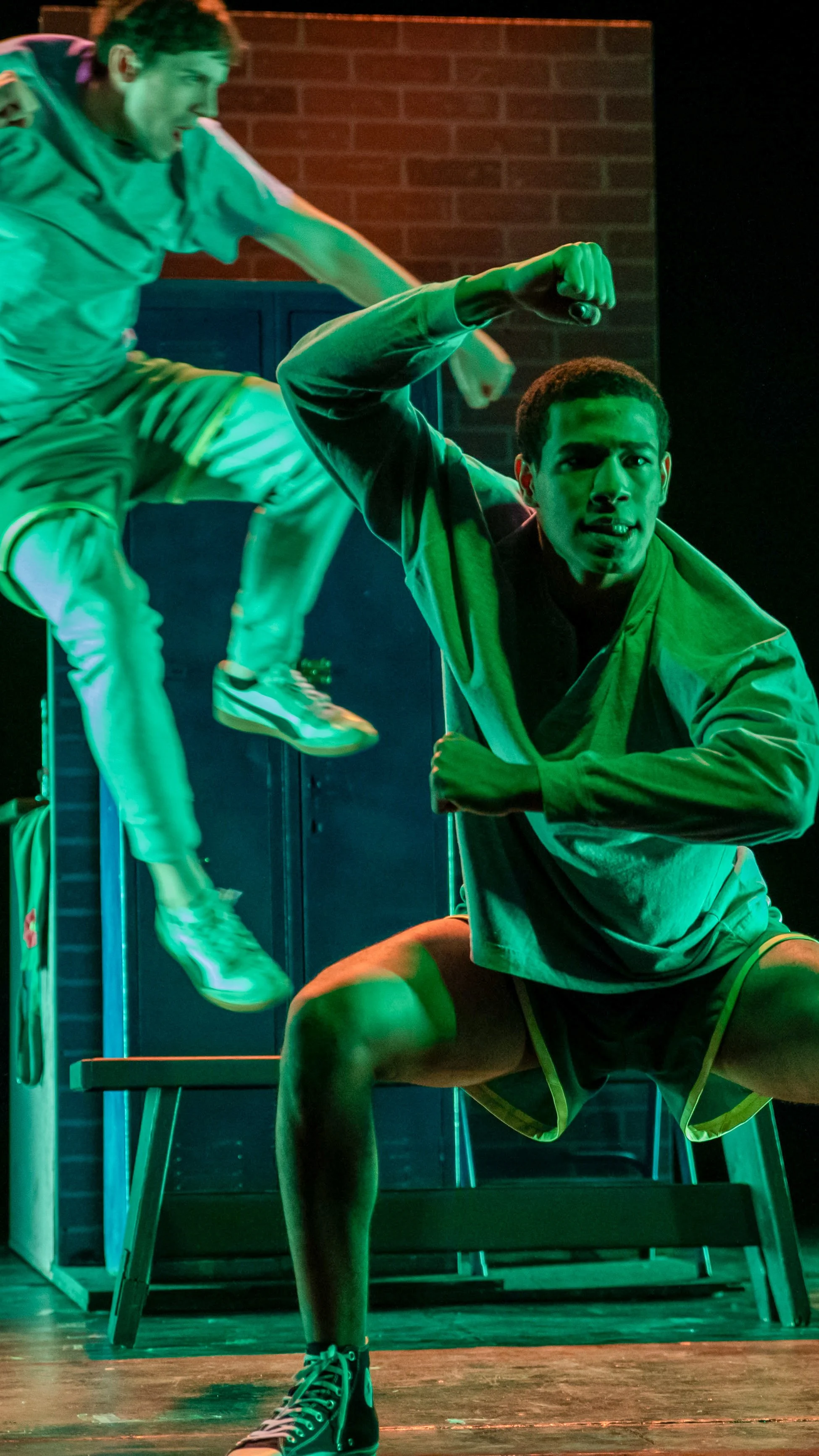 Three performers leap and brace in a green-lit action sequence from Let the Right One In.