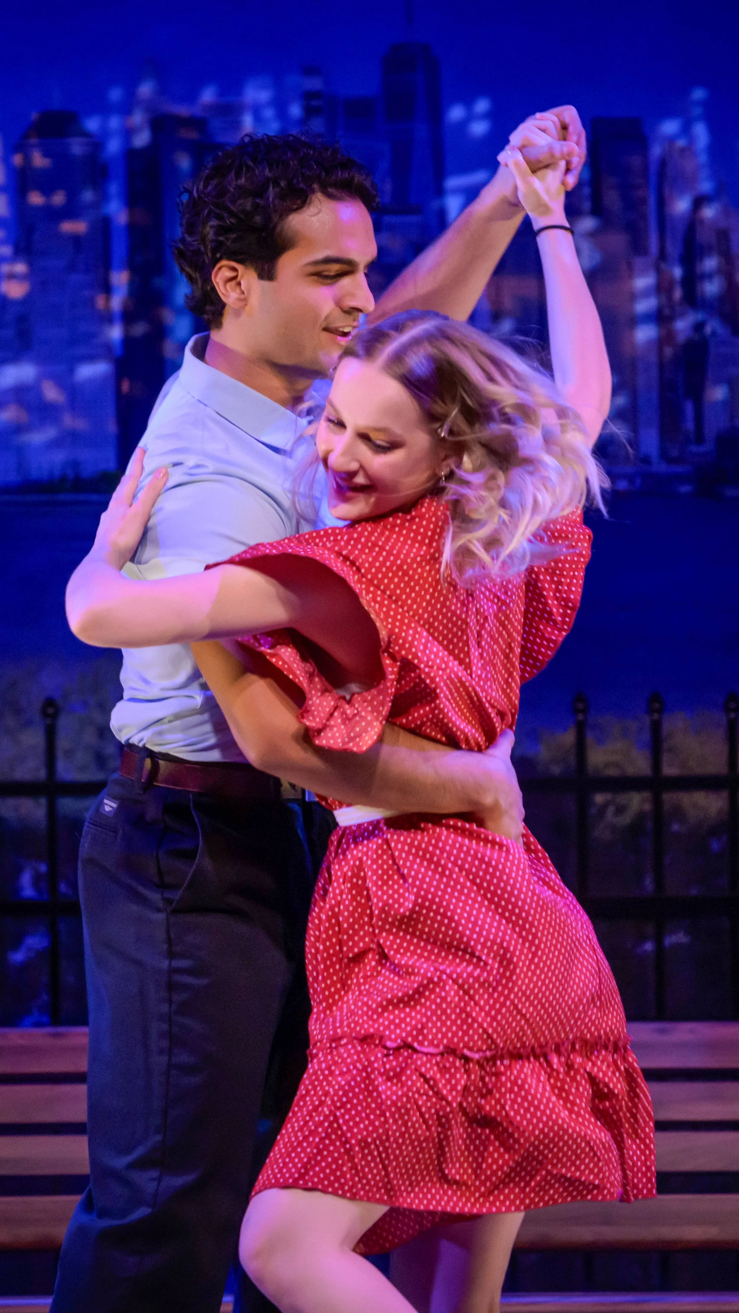 Two performers dance together against a city skyline in The Waterfront.
