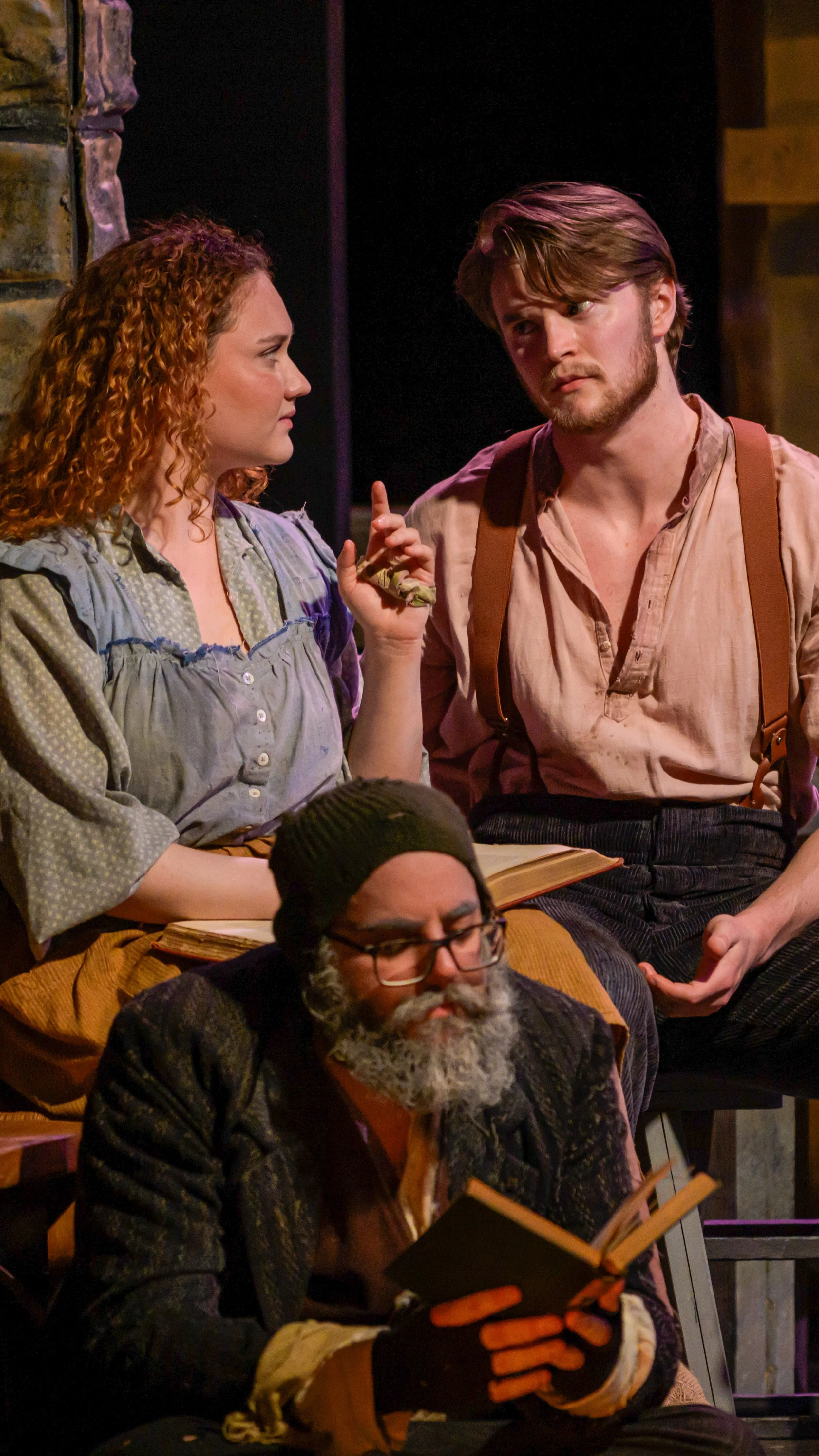 Three performers confer on the rustic wooden set of Translations.