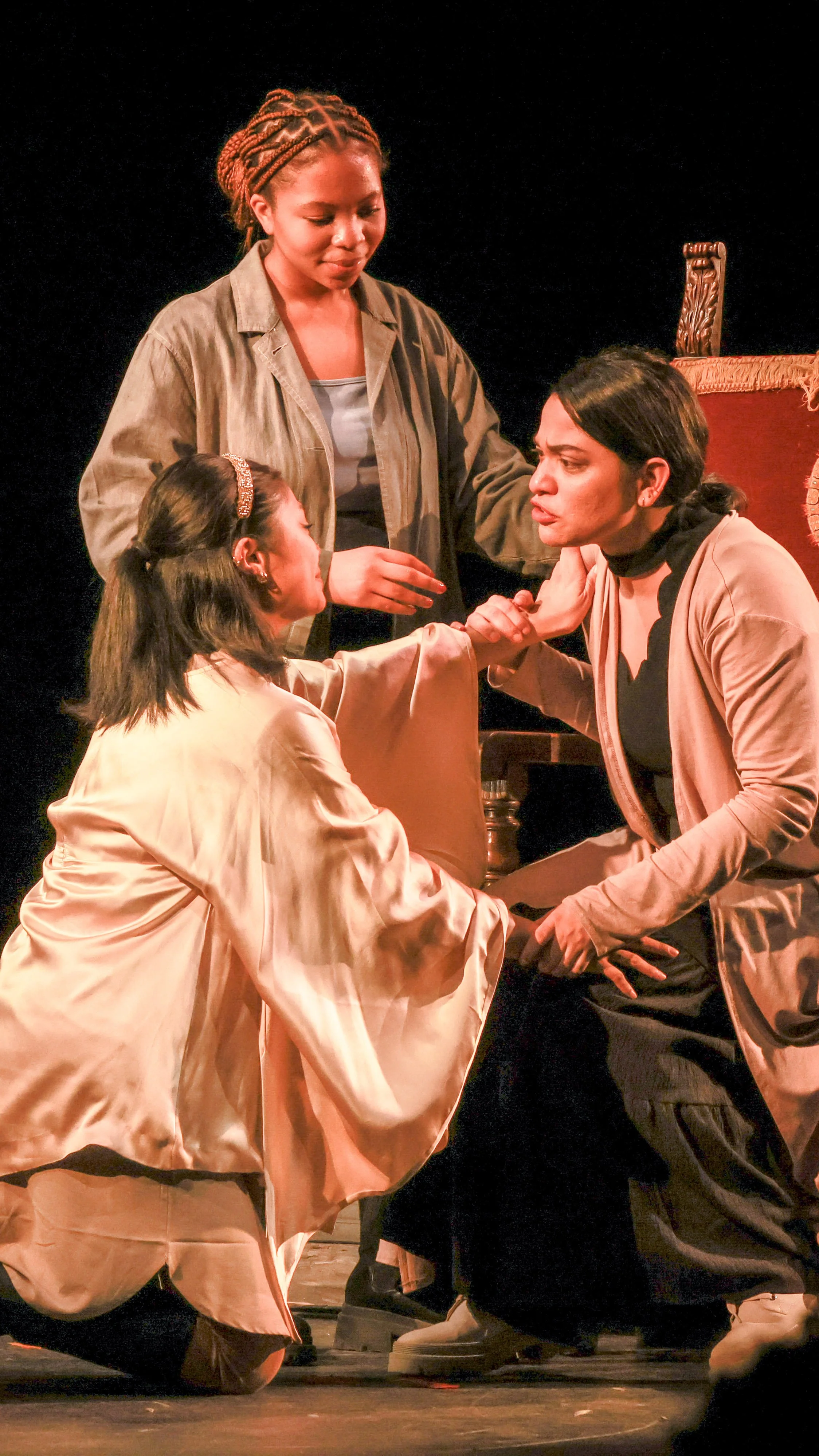 Three performers kneel together in an intimate scene from LEAR.