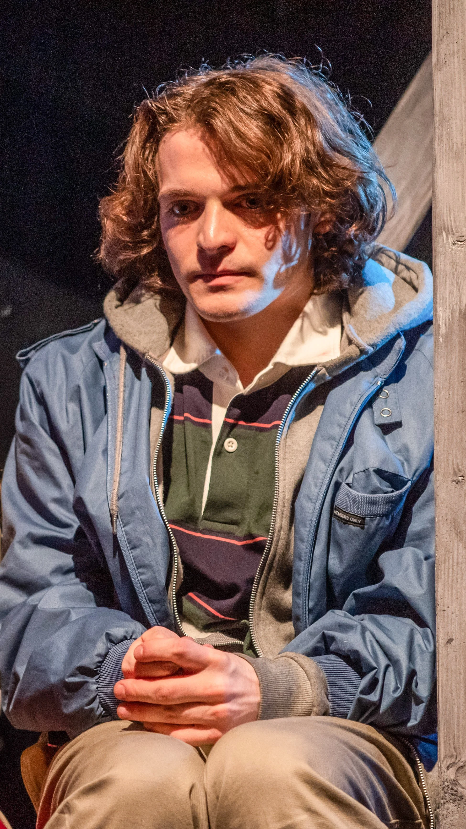 Seated performer in layered winter clothes looks forward in Let the Right One In.