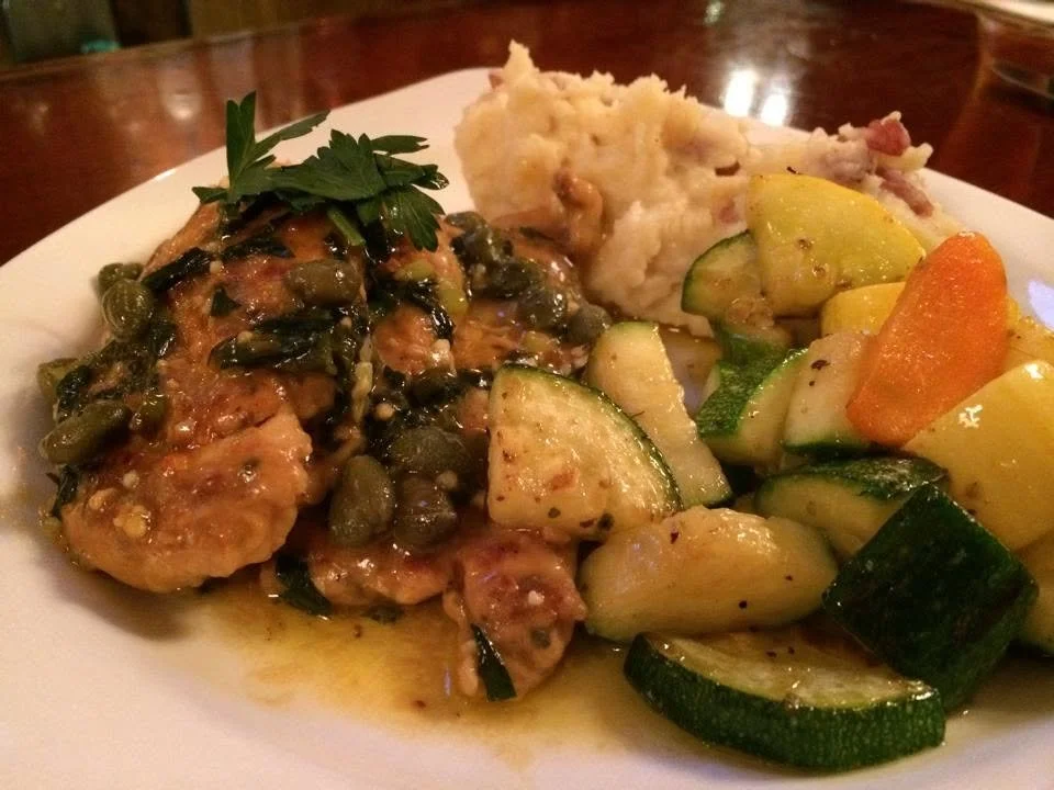 Sauced entree plated with mashed potatoes and mixed vegetables.