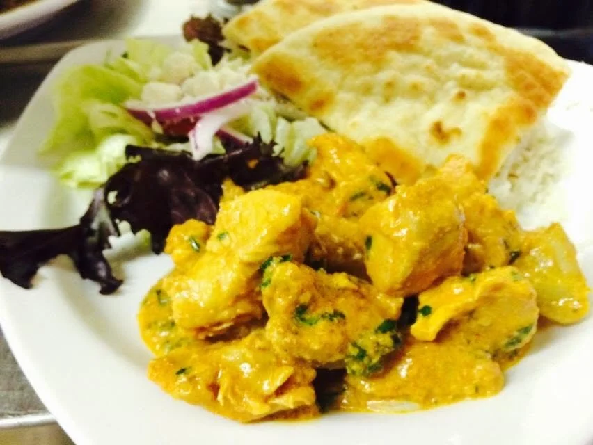 Yellow-sauced entree plated with salad and flatbread.