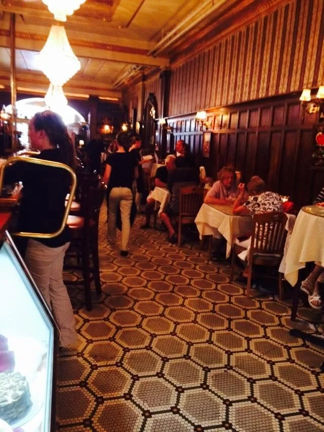 Guests at tables in the wood-paneled dining room beneath hanging lights.
