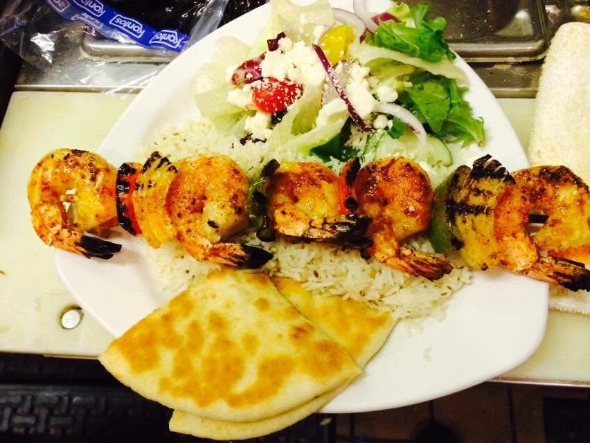 Grilled skewers served over rice with a side salad and flatbread.