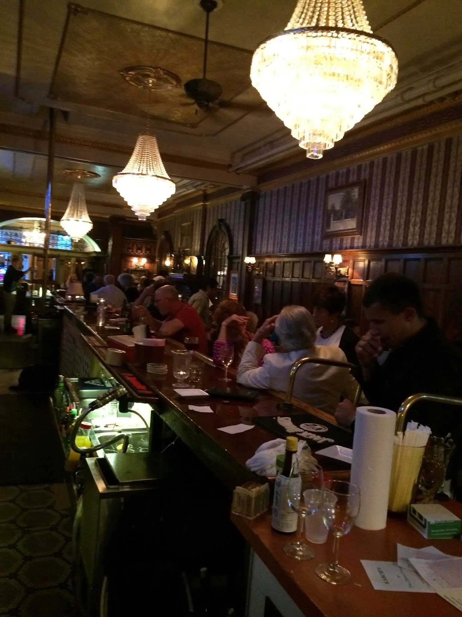 Guests seated at the wooden bar beneath chandeliers at Ka-bobs at The Option House.