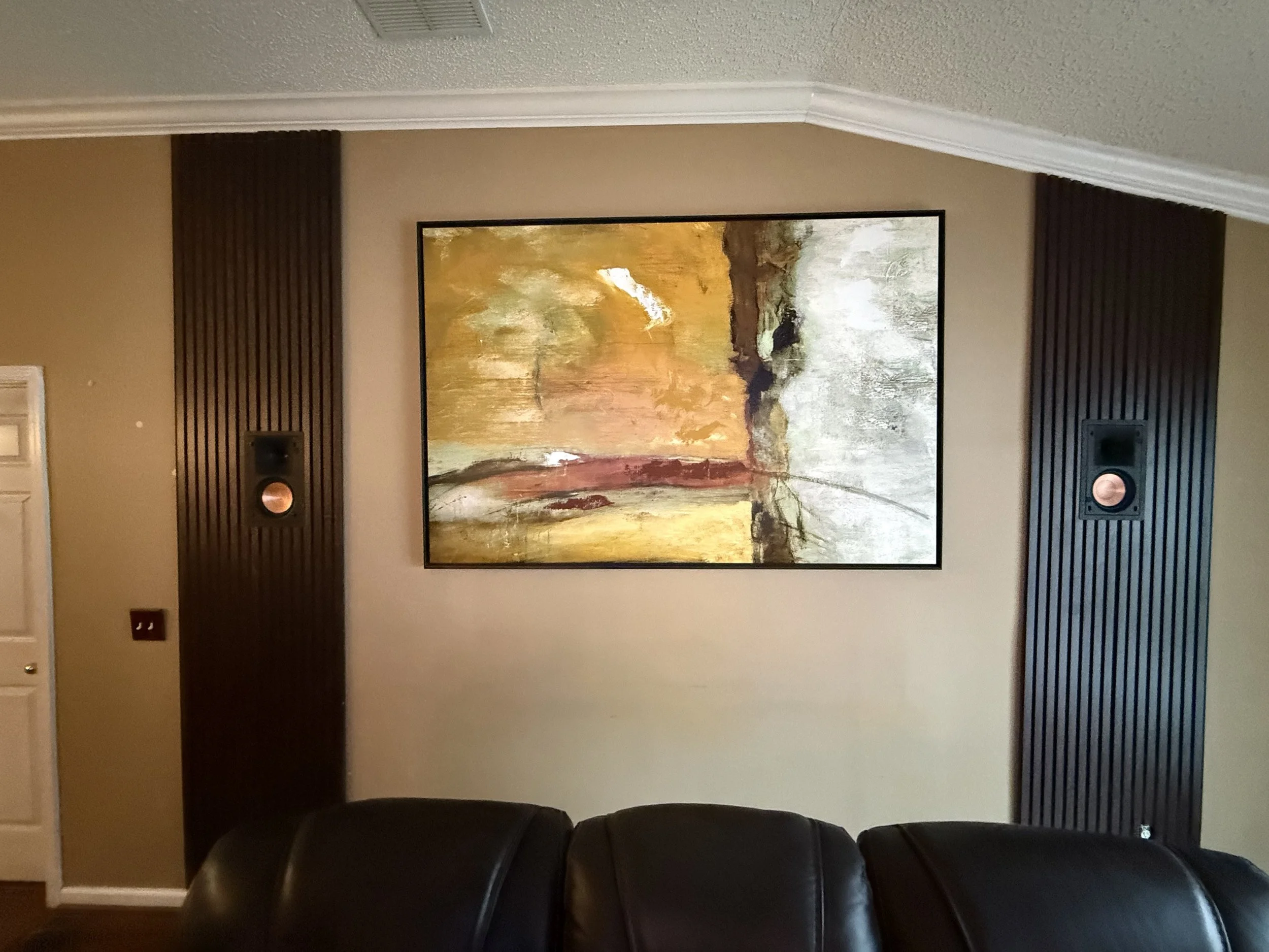 Pair of rear in-wall speakers fitted into slat wall panels, photographed with grilles removed