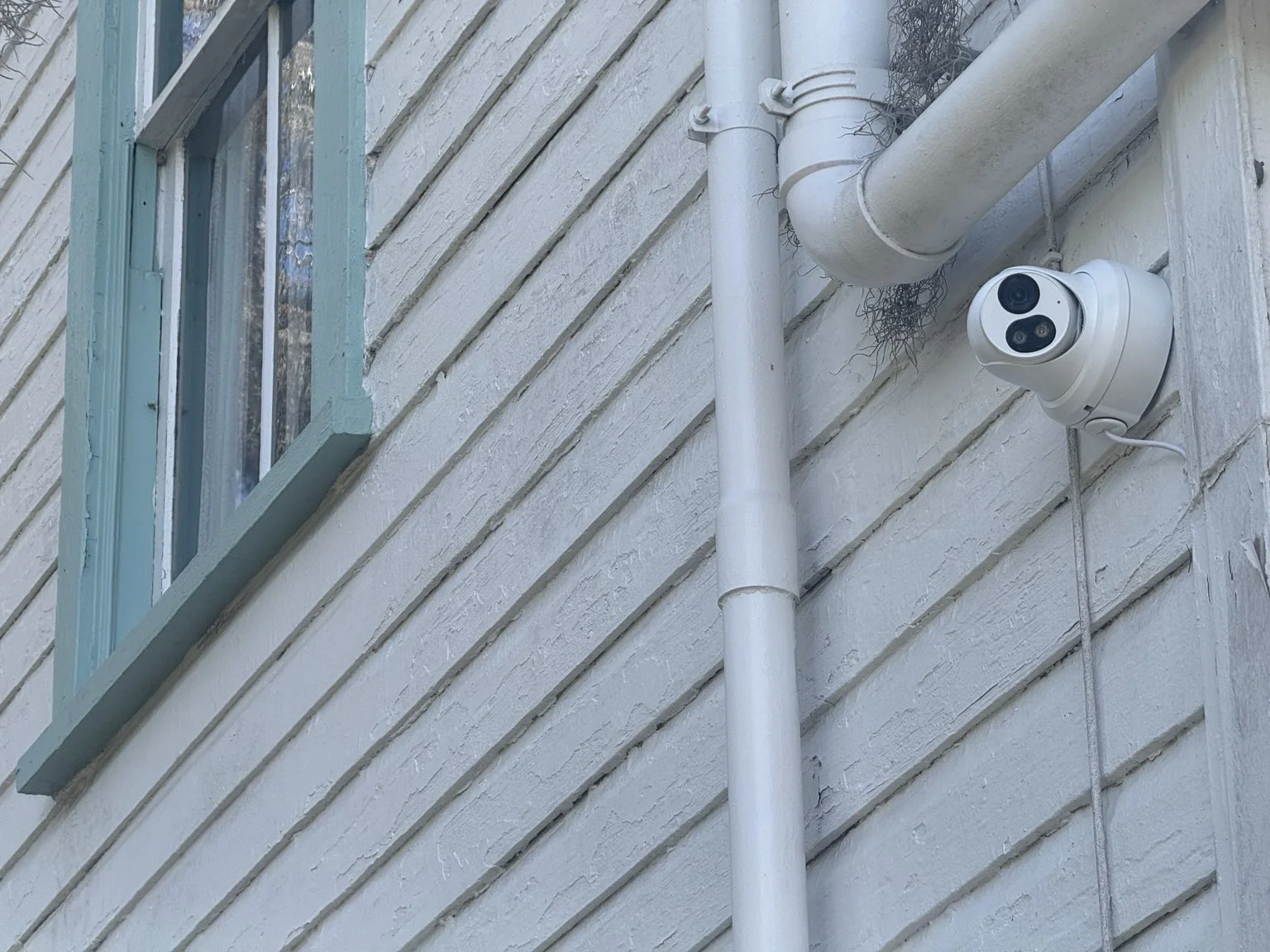 Installed camera and exterior cable route beside the window.