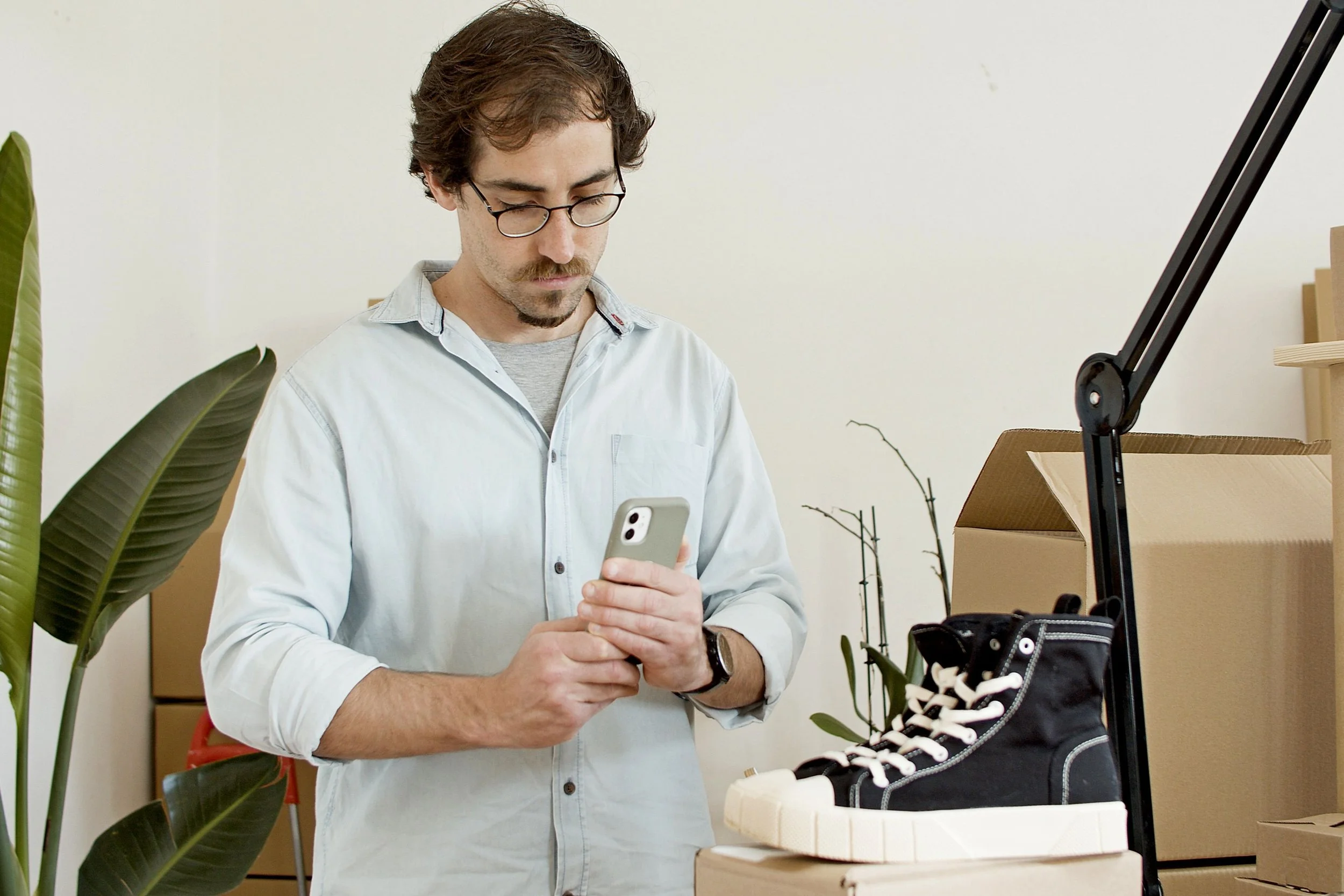 Busy business owner taking a photo of shoes he made for social media with a frown.