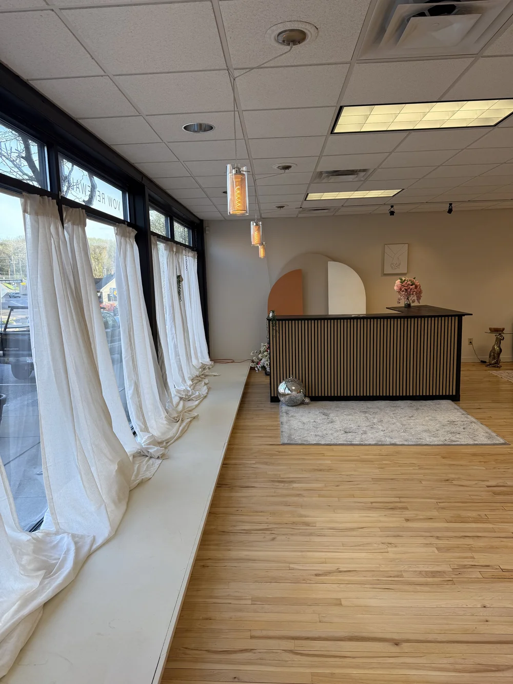 The Vow House welcome desk beside tall windows, soft curtains, and disco ball accents