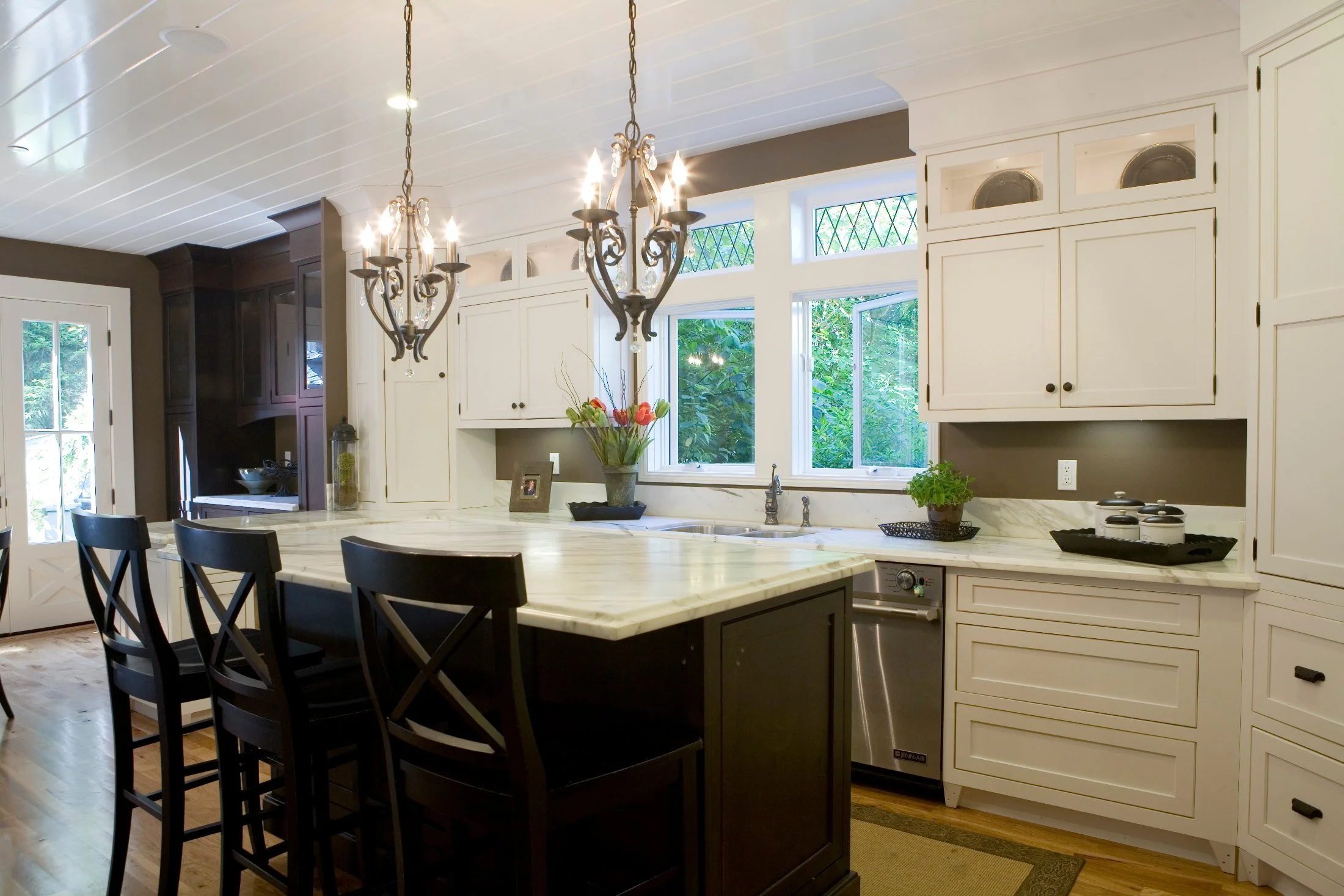 Custom kitchen with white cabinetry and dark island built by Bay Insight Builders