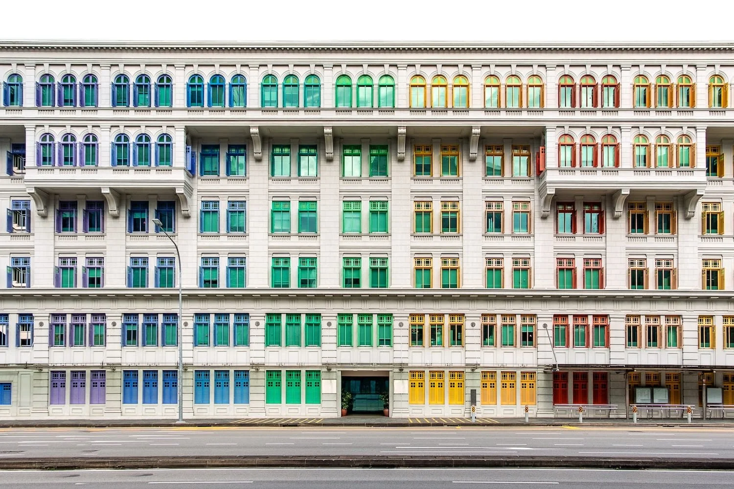 Historic Singapore building with rainbow gradient of colorful window shutters showing architectural preservation