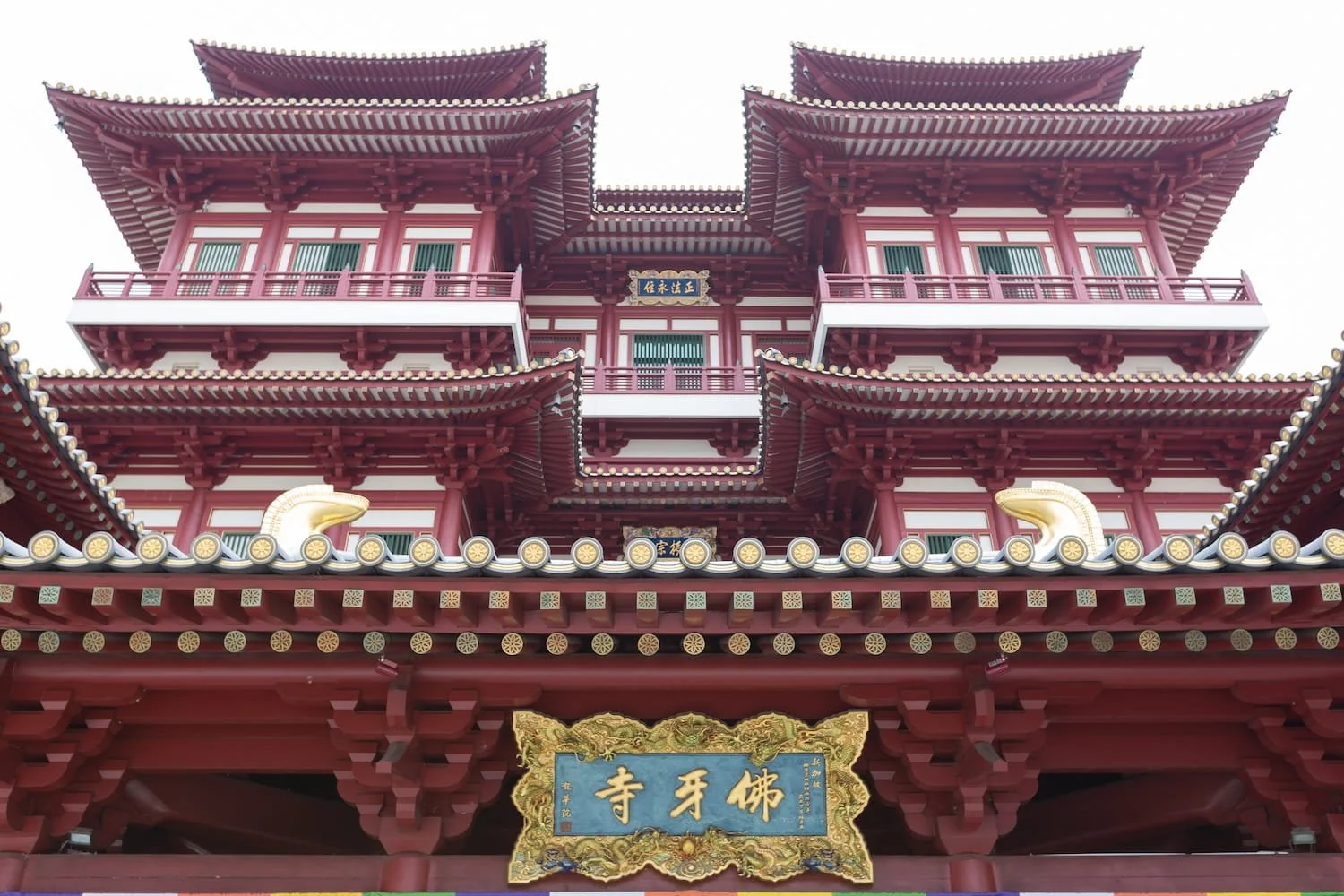 Detailed view of Buddha Tooth Relic Temple's symmetrical red architecture and golden ornamental plaque