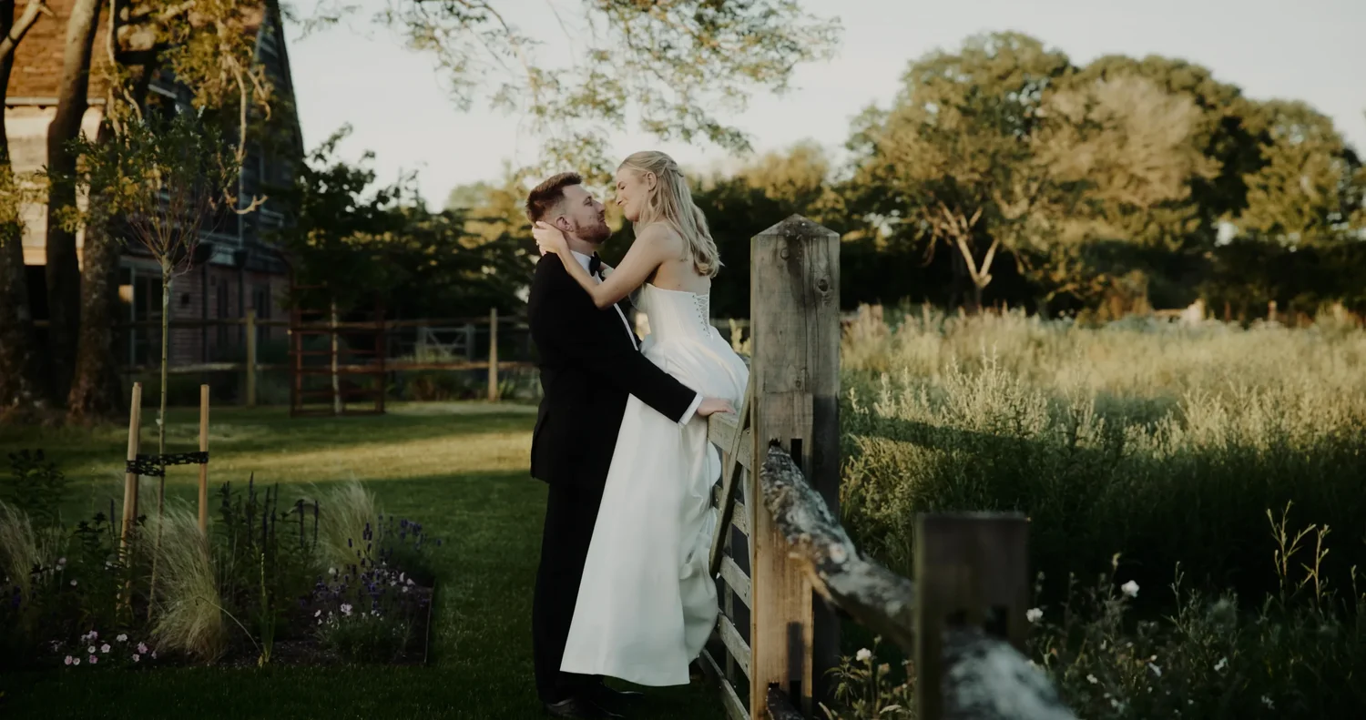 Emily and Ryan embracing beside a wooden gate at Rackleys Chiltern Hills