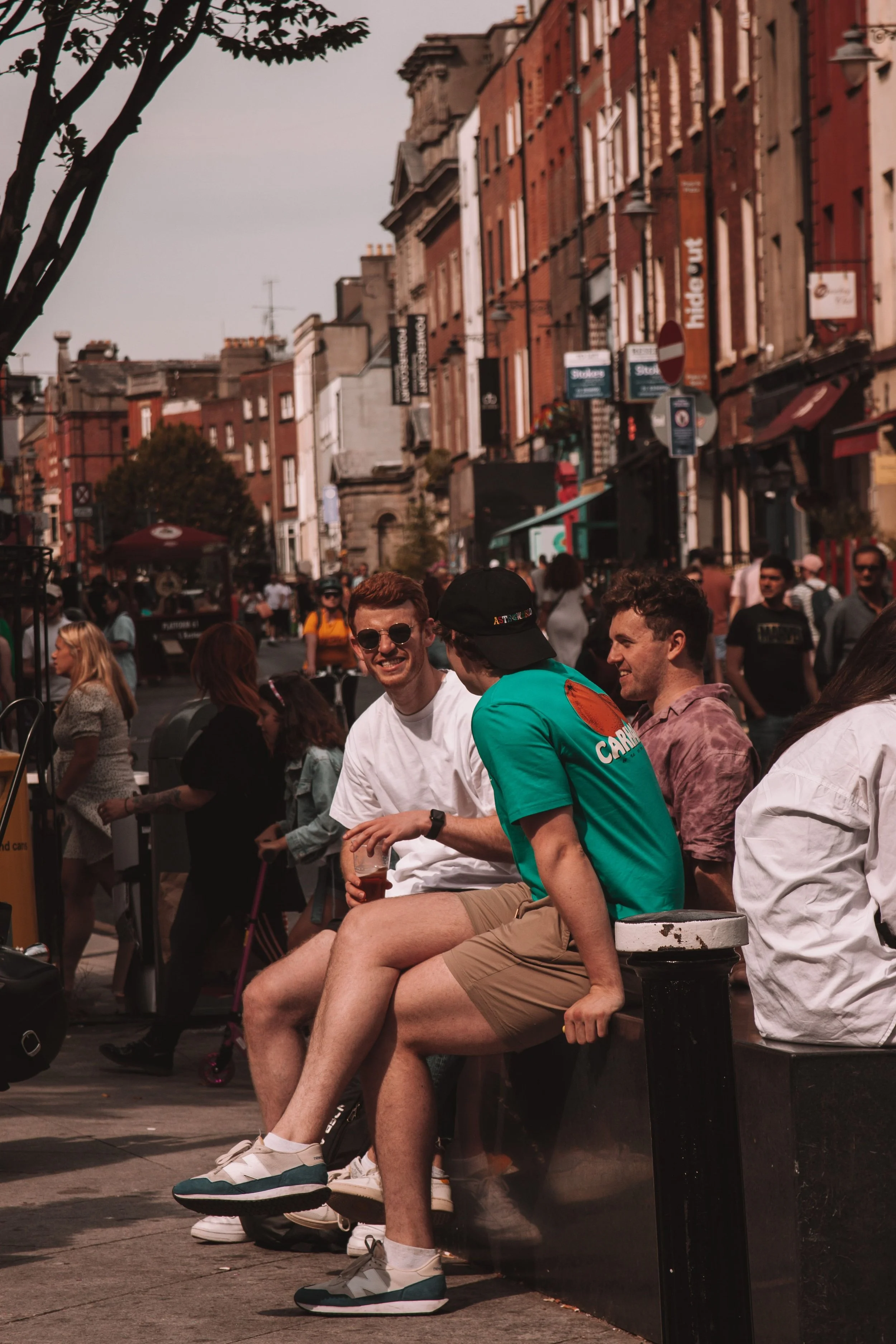 Three men sitting together on a bench and talking outdoors.