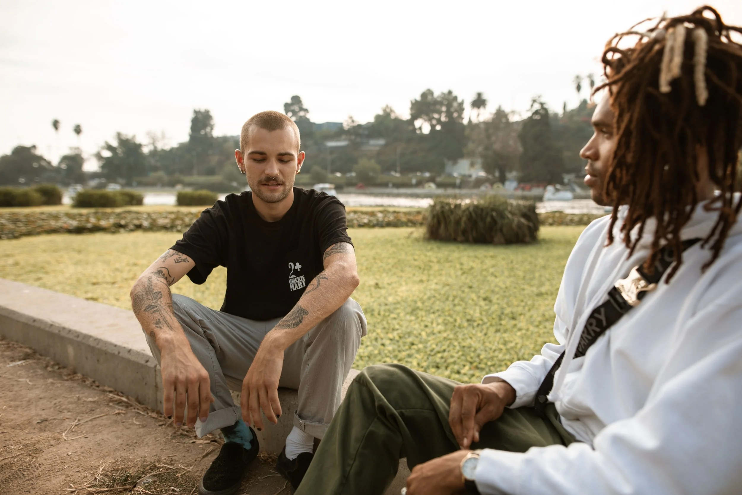 Two men sitting together and talking in a sunny park.