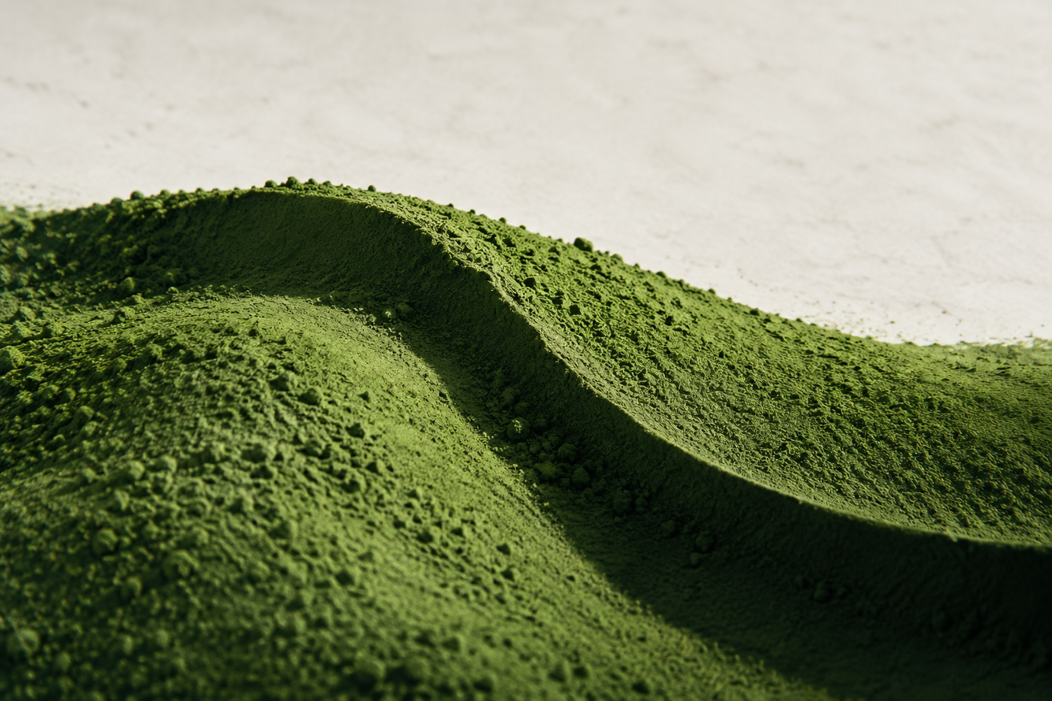 A sculptural ridge of matcha powder, like a miniature green landscape — conceptual editorial image