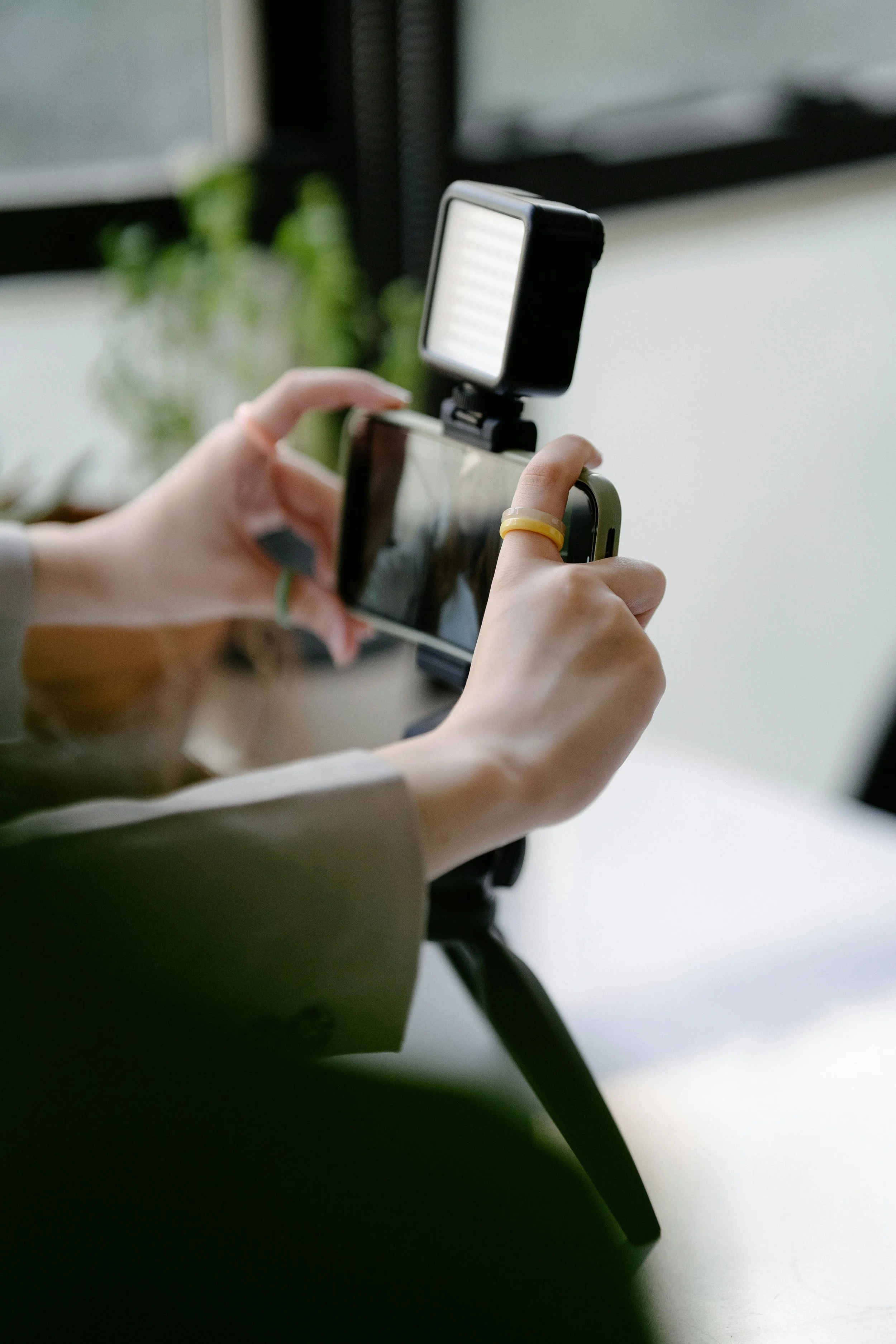 Photo of a woman holding a camera creating content on a desk