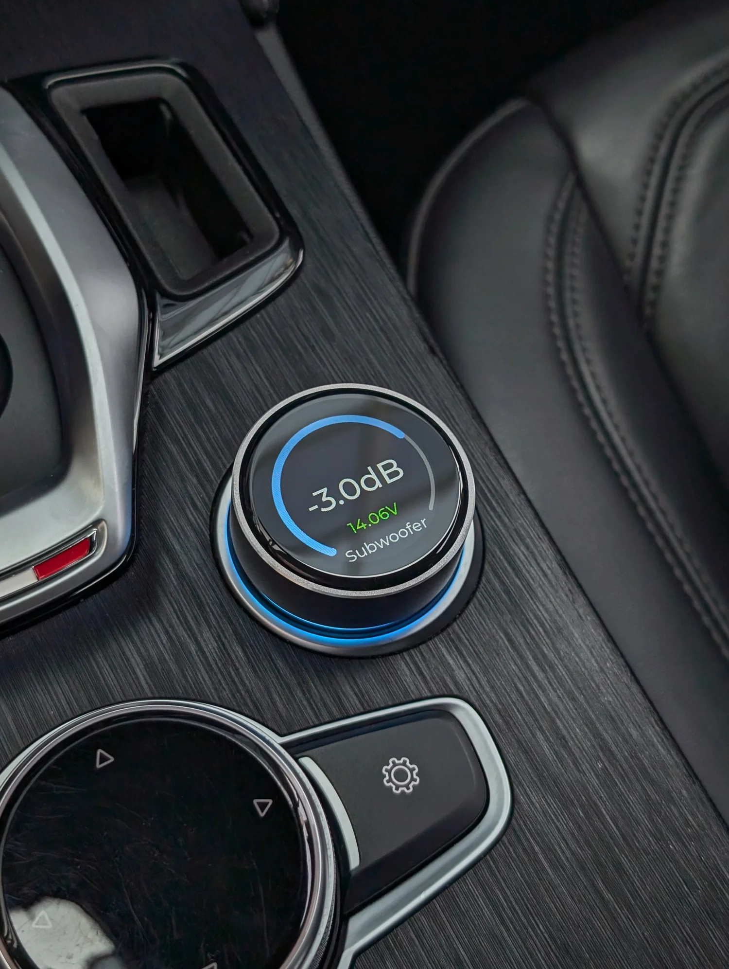Cuore One DSP controller installed in a car centre console, showing subwoofer level on its display
