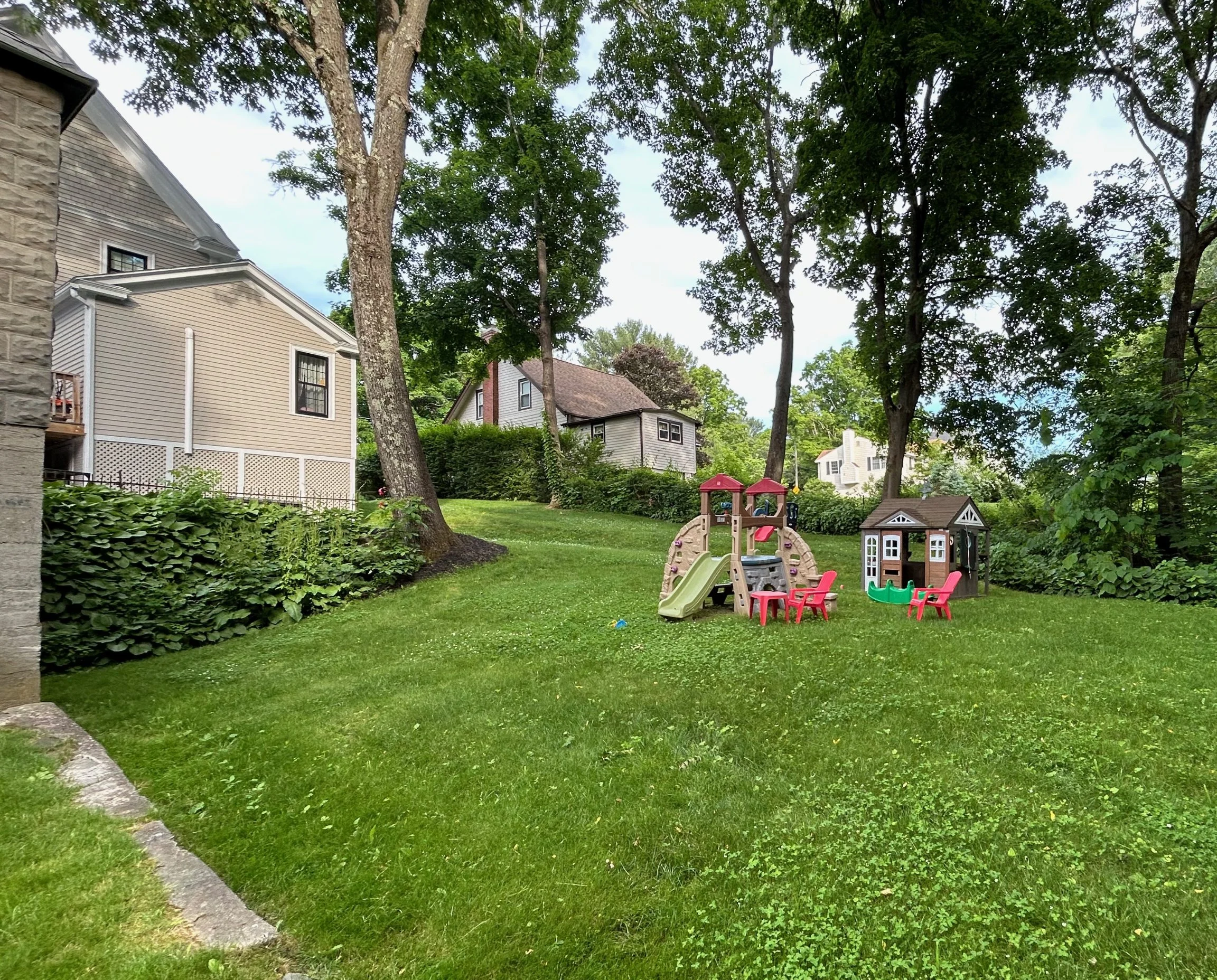 Before photo of the backyard with open grass and children's play structures.