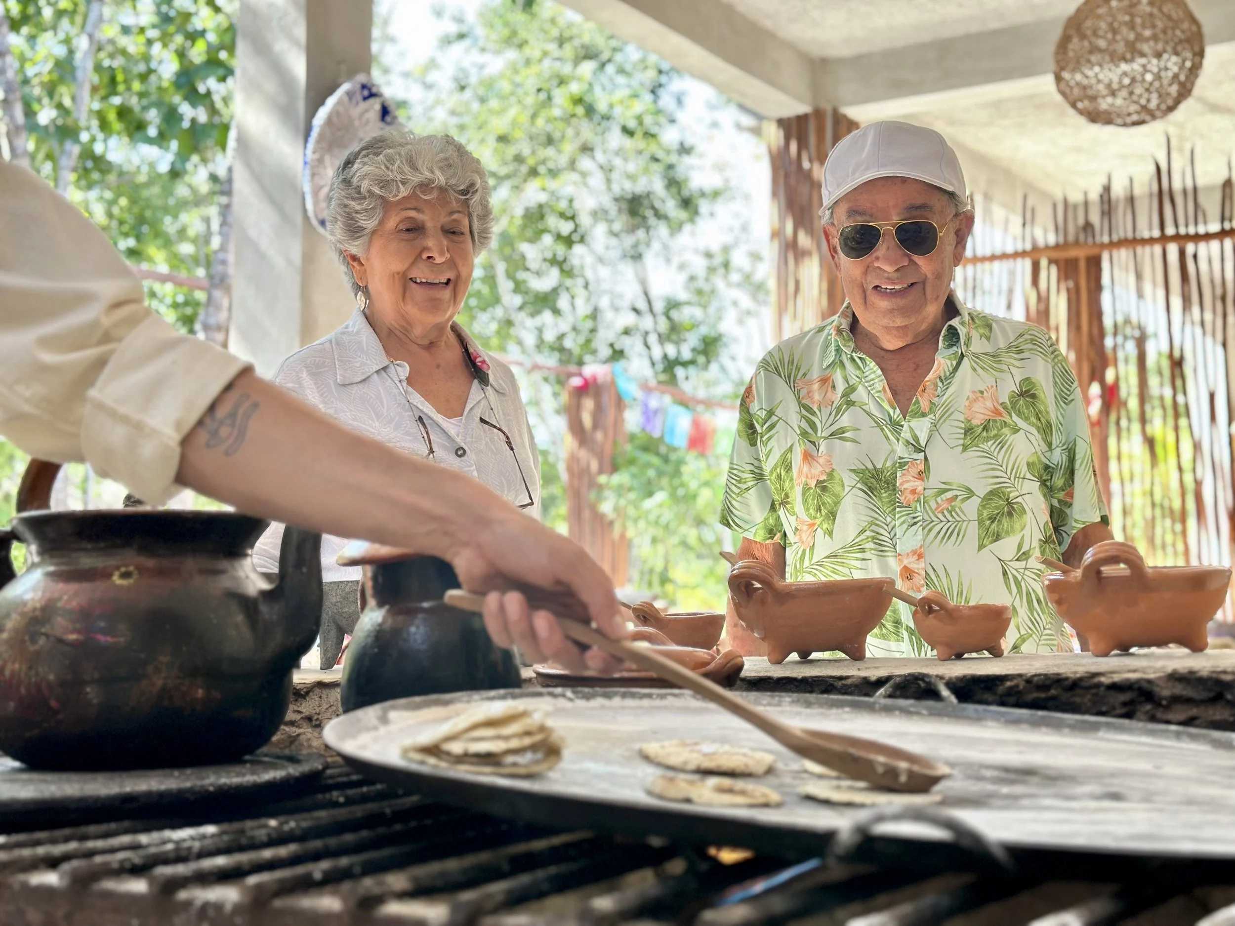 Hands pressing fresh tortillas on a traditional comal