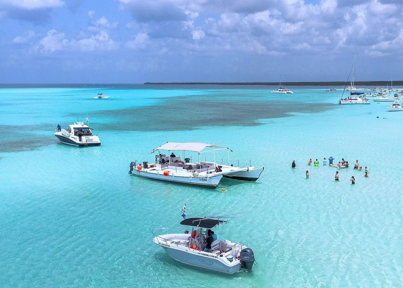 Crystal-clear turquoise waters of Cozumel with boats and swimmers