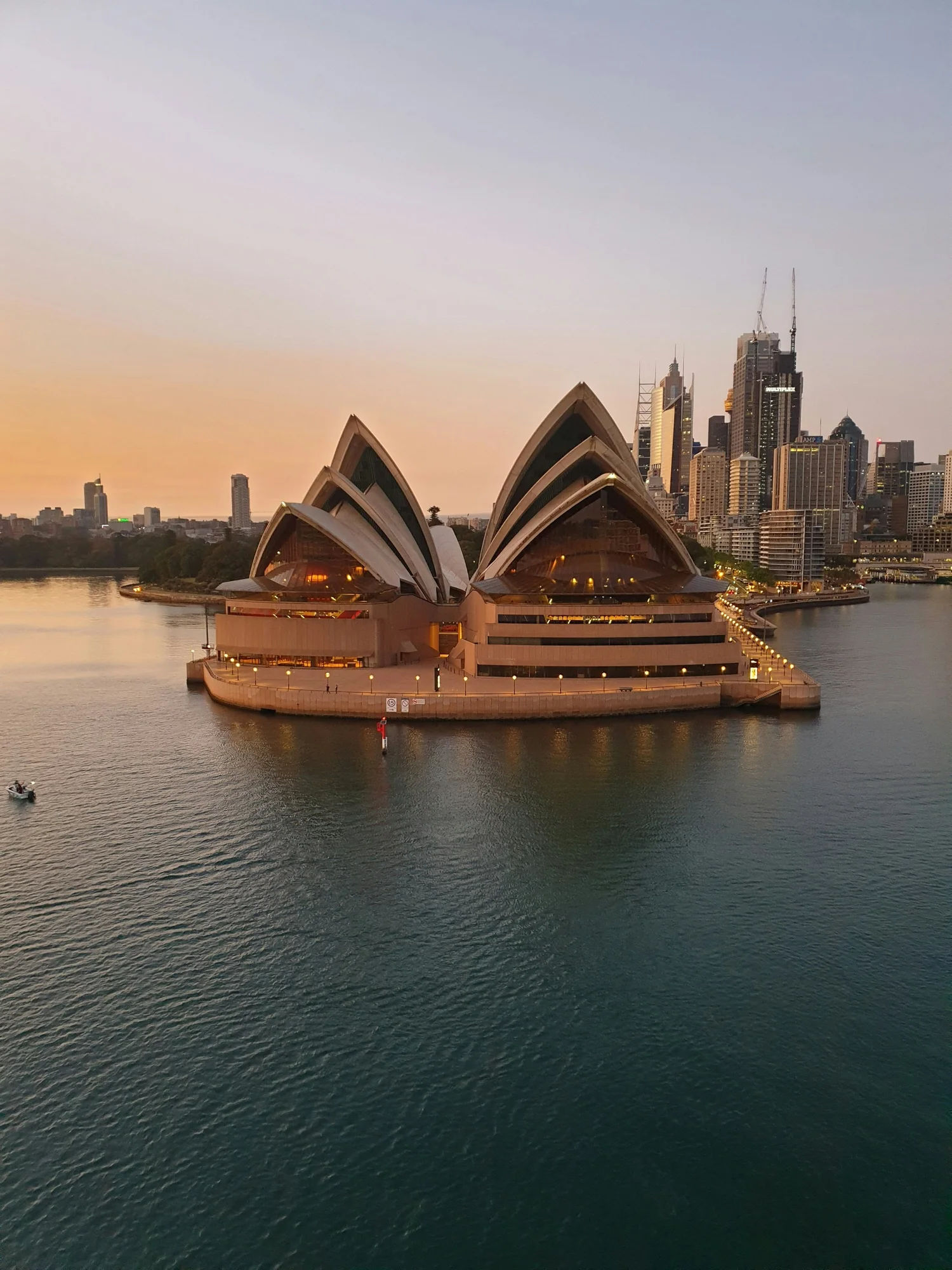 The Sydney Opera House at dusk from above, with the city skyline behind it