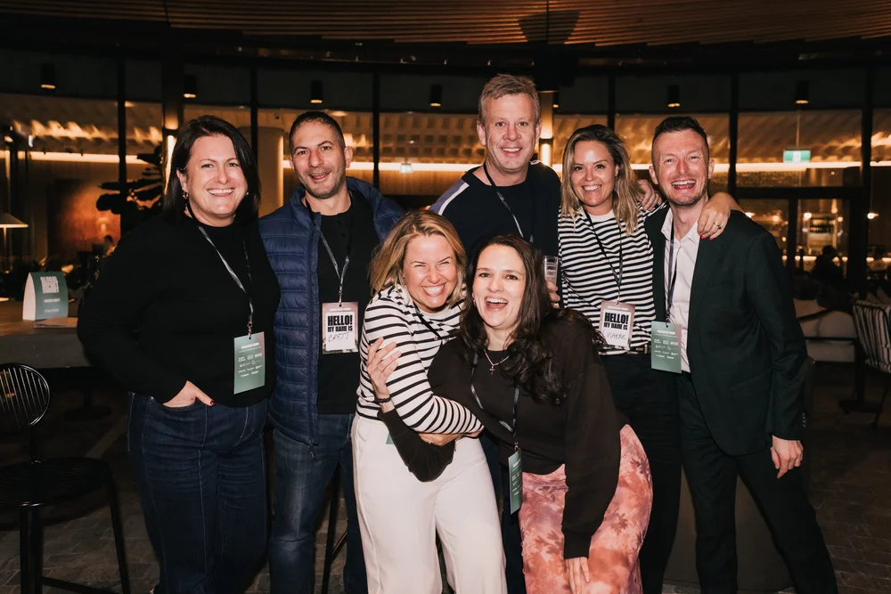 A group of guests with lanyards laughing together at the launch party