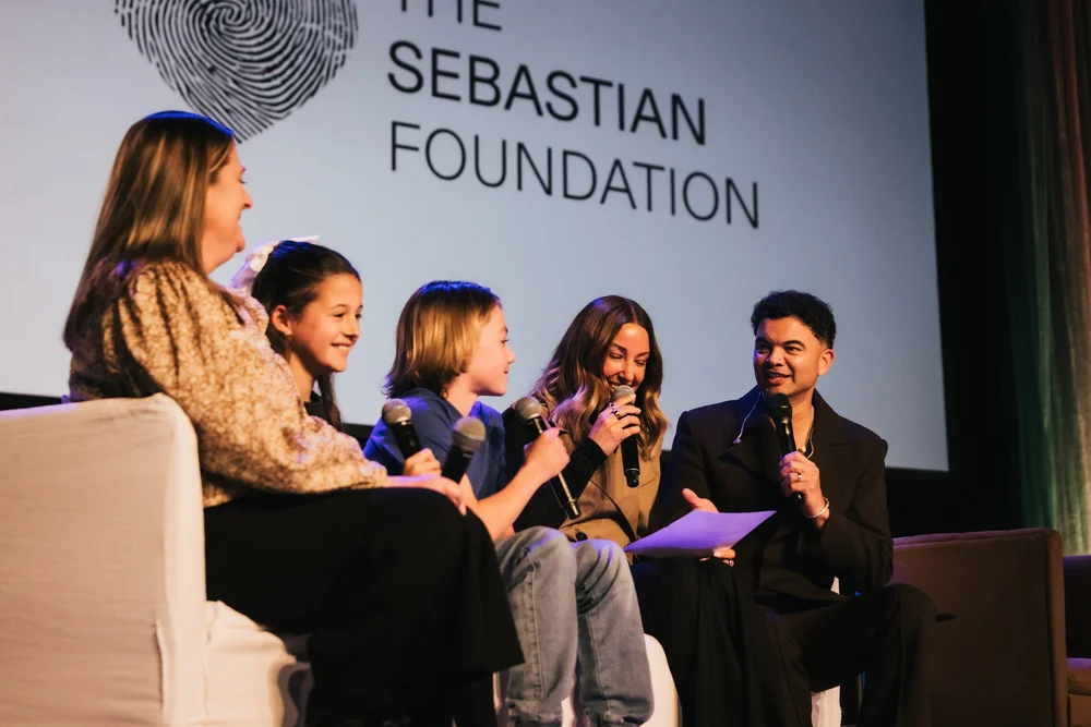 Guy Sebastian and young guests in conversation on stage in front of The Sebastian Foundation screen at Impact Live