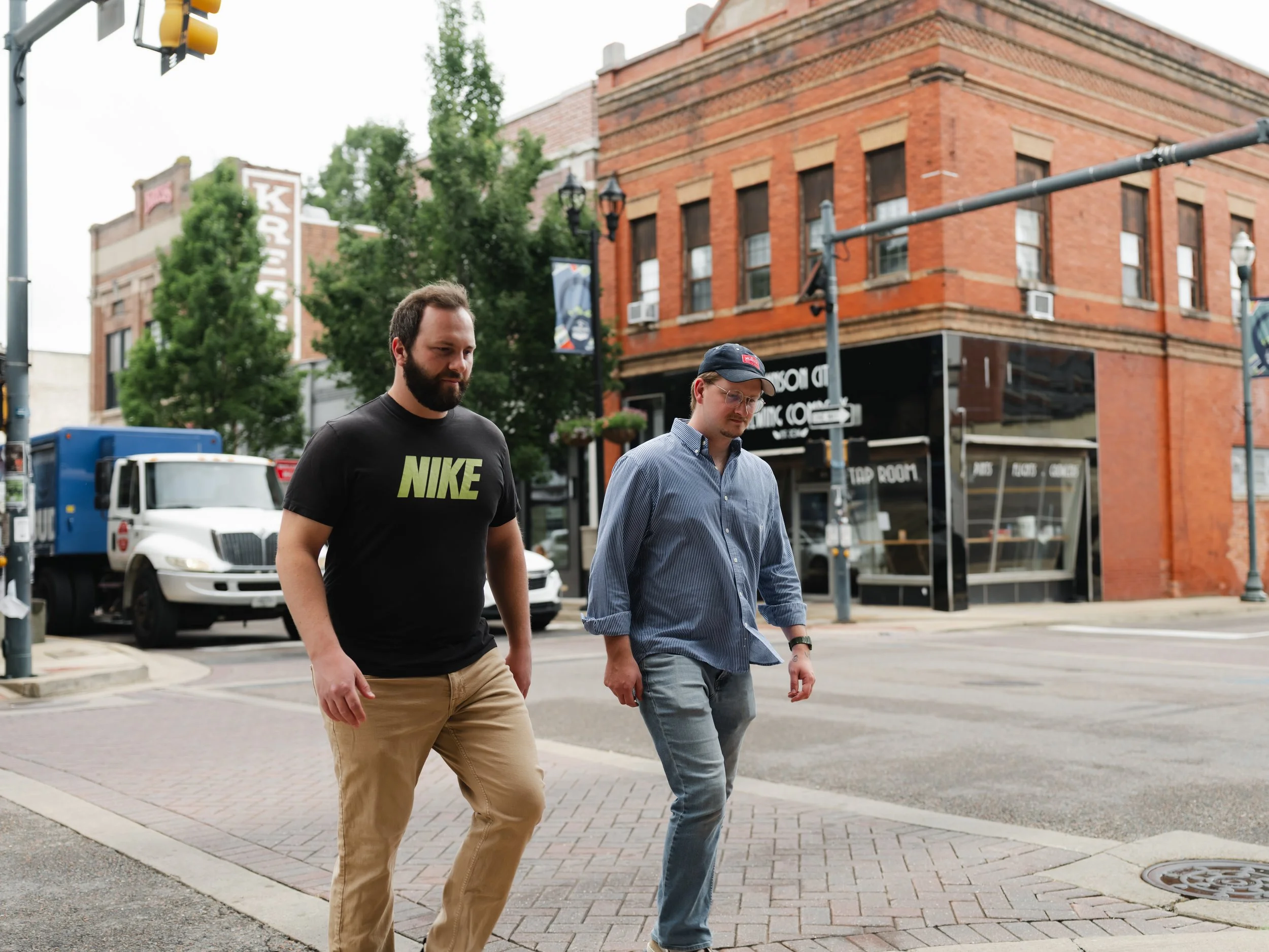 Two men walking across a brick crosswalk in downtown Johnson City