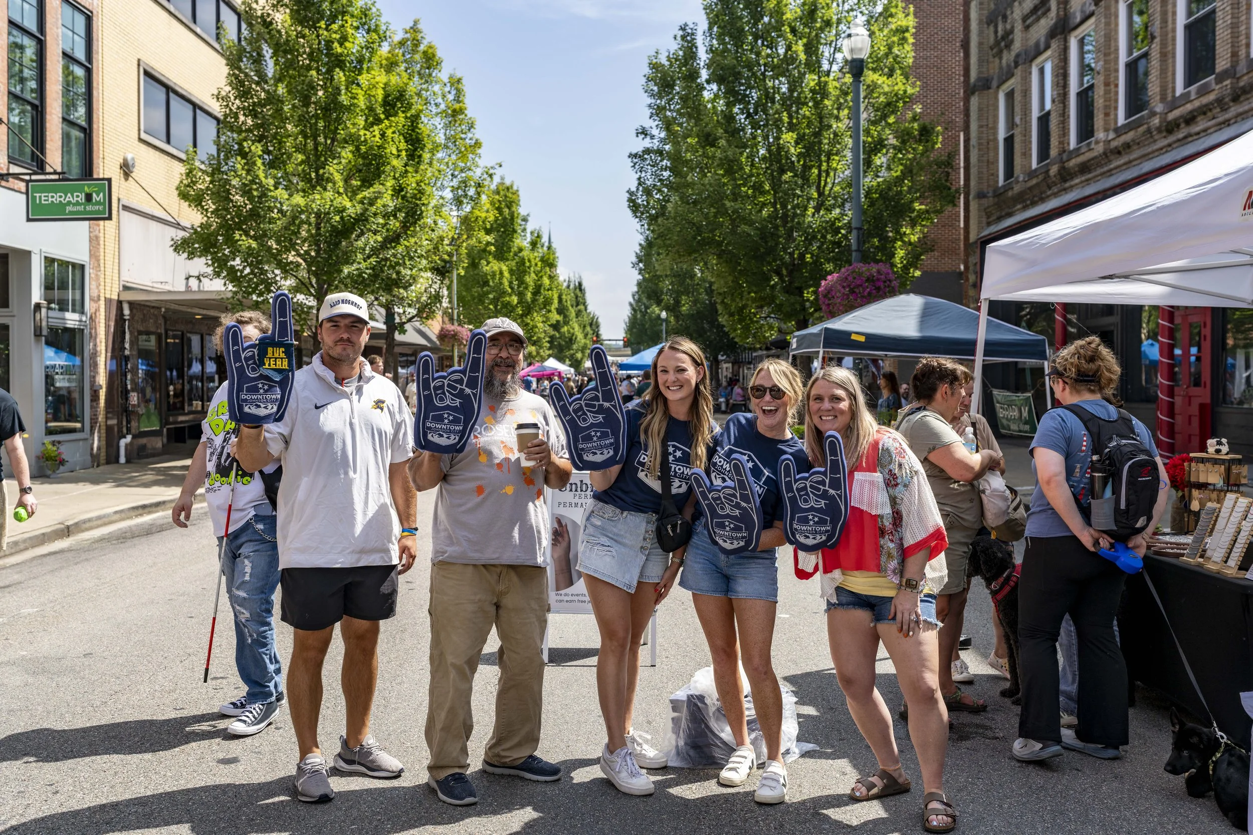 A group holding Downtown Johnson City foam fingers at a street festival