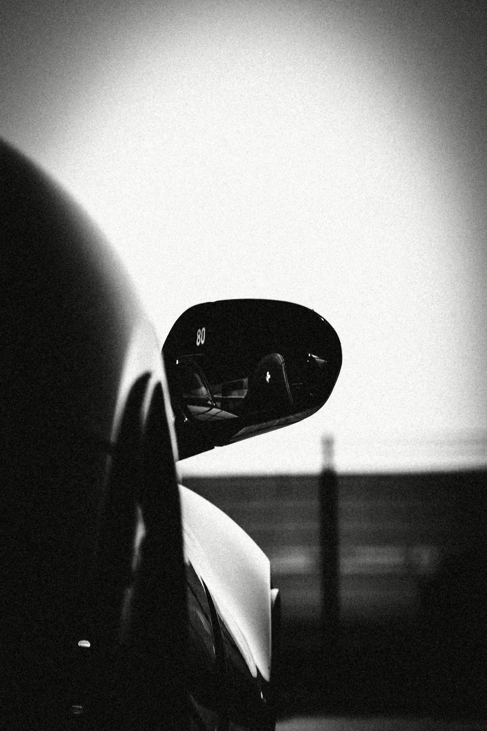 A wing mirror against an empty white sky, high-contrast black and white