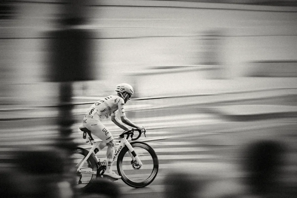 A rider on a yellow bike sweeping through Paris, the city dragged into silver streaks
