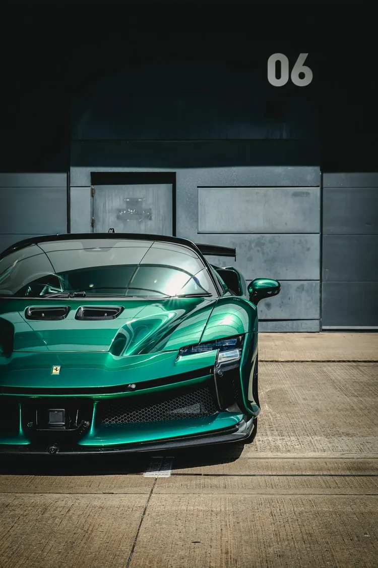 A green sports car under a garage number, square on