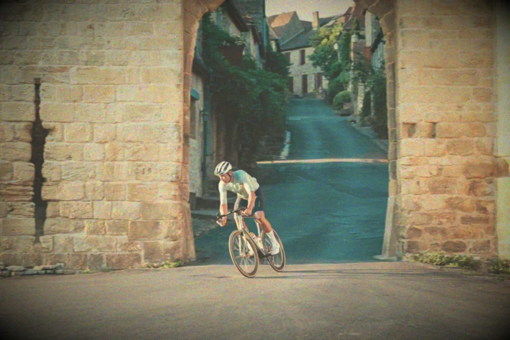 James riding out of a stone archway in a medieval village, pastel Autochrome colour