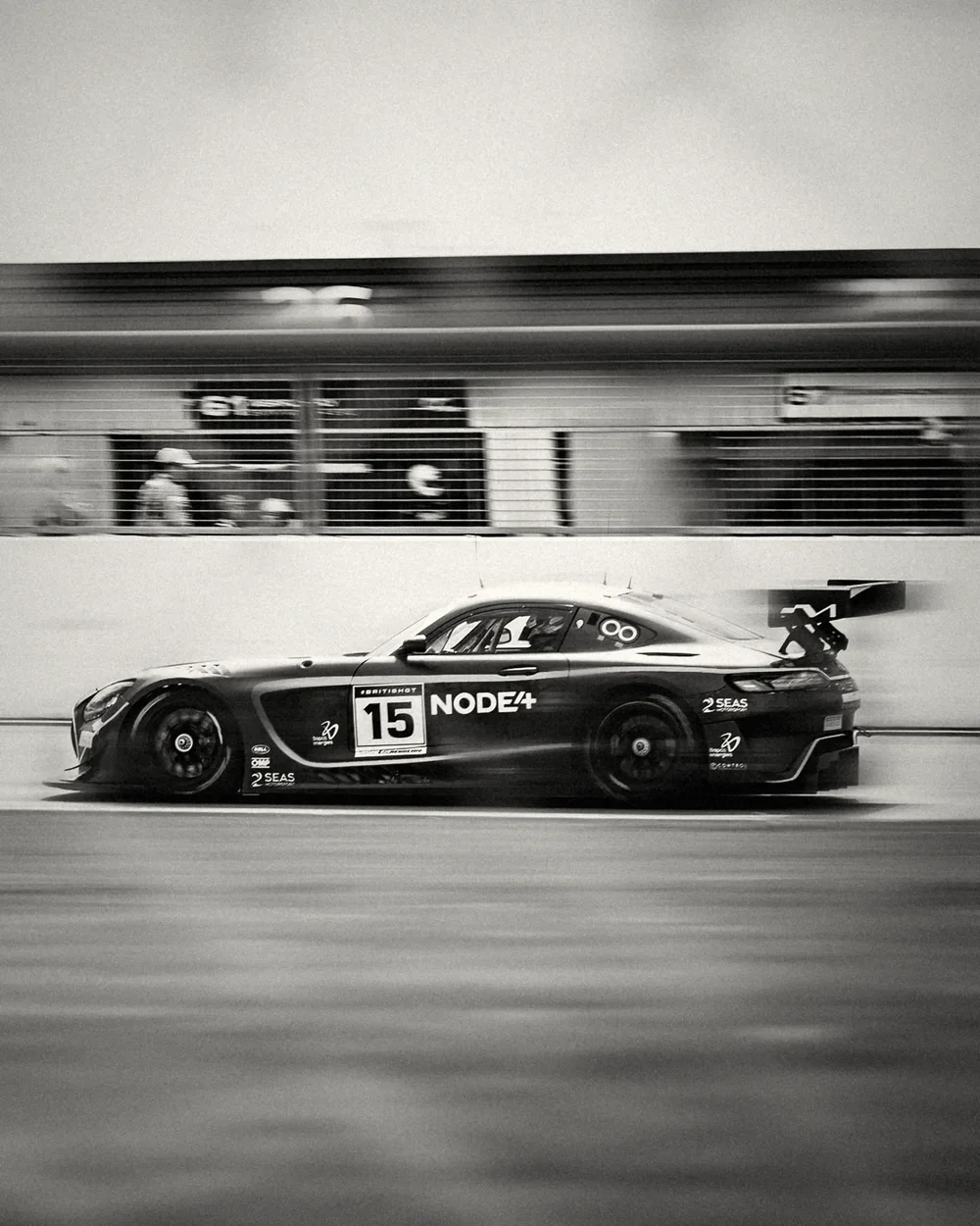 The Mercedes past the pit garages, background dragged into speed lines, silver black and white