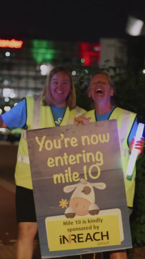 Volunteers laughing beside a sign reading You are now entering mile 10
