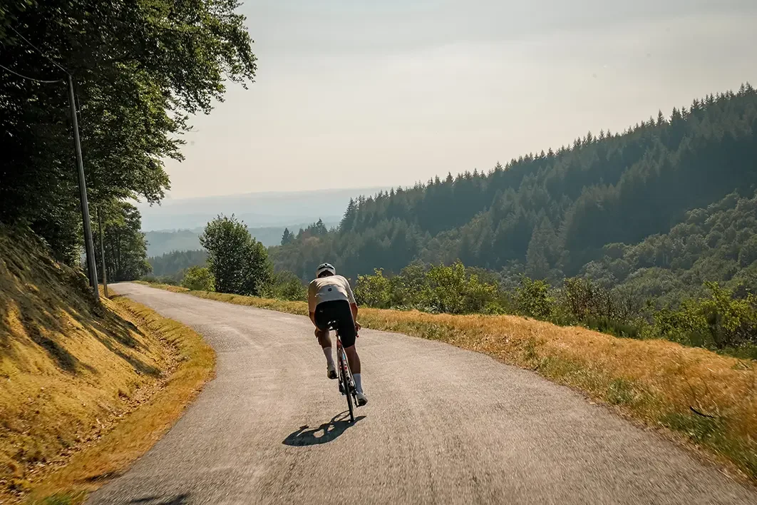 James Golding climbing a forested road on the Tour de France route during 2112