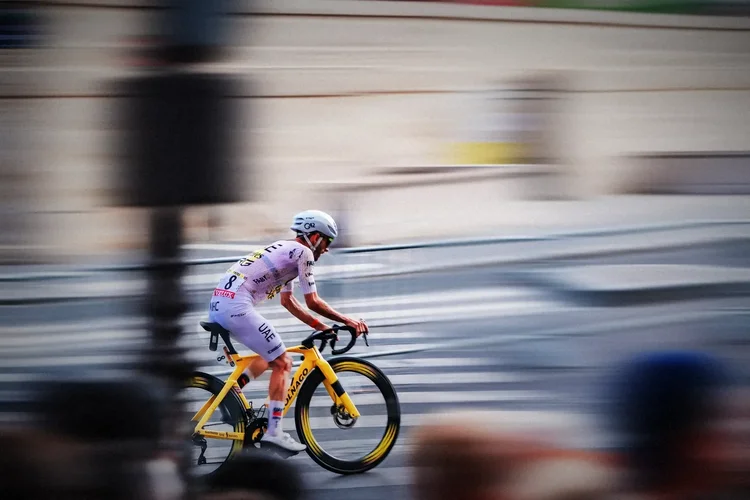 A rider on a yellow bike against a streaked Paris, in colour