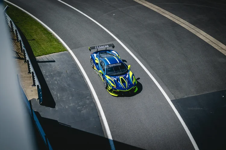 A blue and yellow race car following the curve of the white line, from above