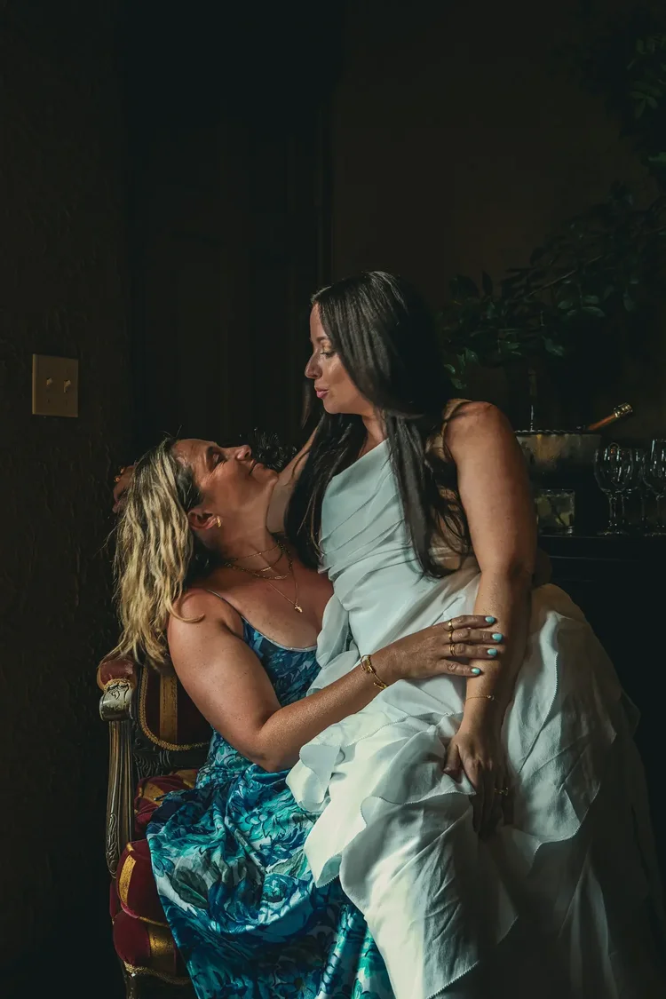 The bride laughing with a friend in a dimly lit room during the evening celebrations
