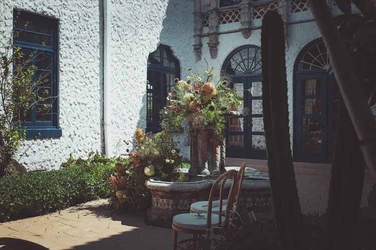 Sunlit courtyard at the Young Mansion with a tiled fountain, dried flower arrangement and bentwood chairs