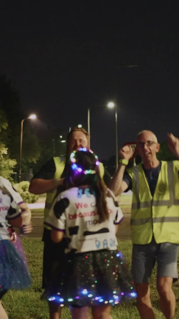 Volunteers laughing beside a mile 10 sign at a night walk