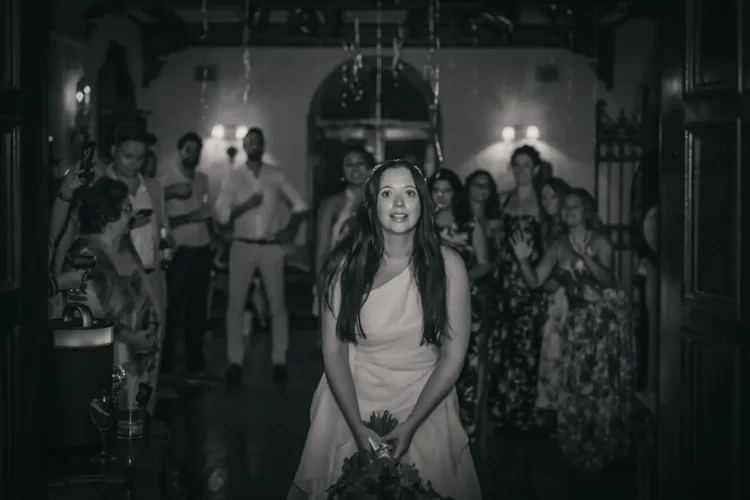 Bride about to throw the bouquet to guests gathered in the hall, black and white