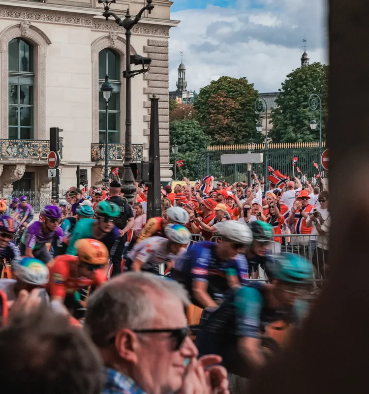Norwegian fans waving flags as the peloton blurs past on the final stage of the Tour de France 2026 in Paris