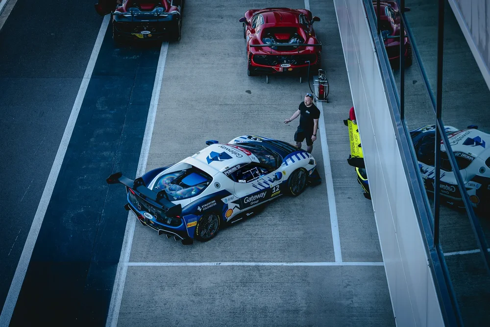 A white GT car in the pit lane, shot from above